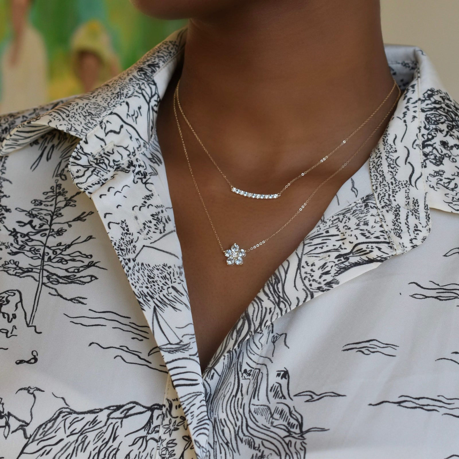 Woman with two gold necklaces including a Rosecliff bar necklace with eleven alternating 2 mm faceted aquamarines & diamonds
