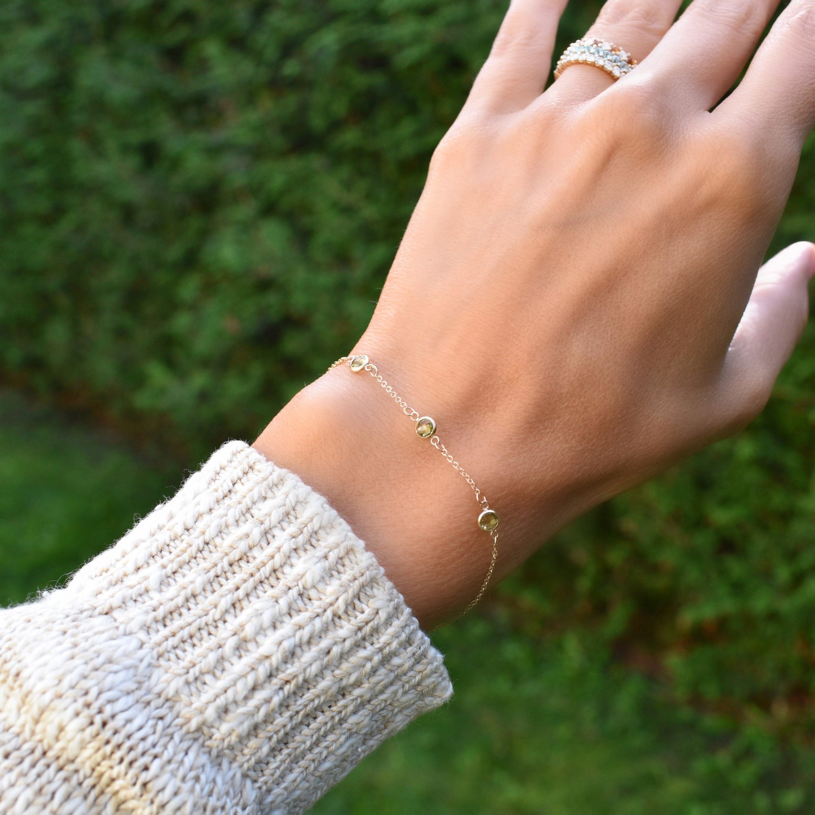 Woman wearing a Bayberry cable chain birthstone bracelet featuring three 4 mm briolette peridots bezel set in 14k gold