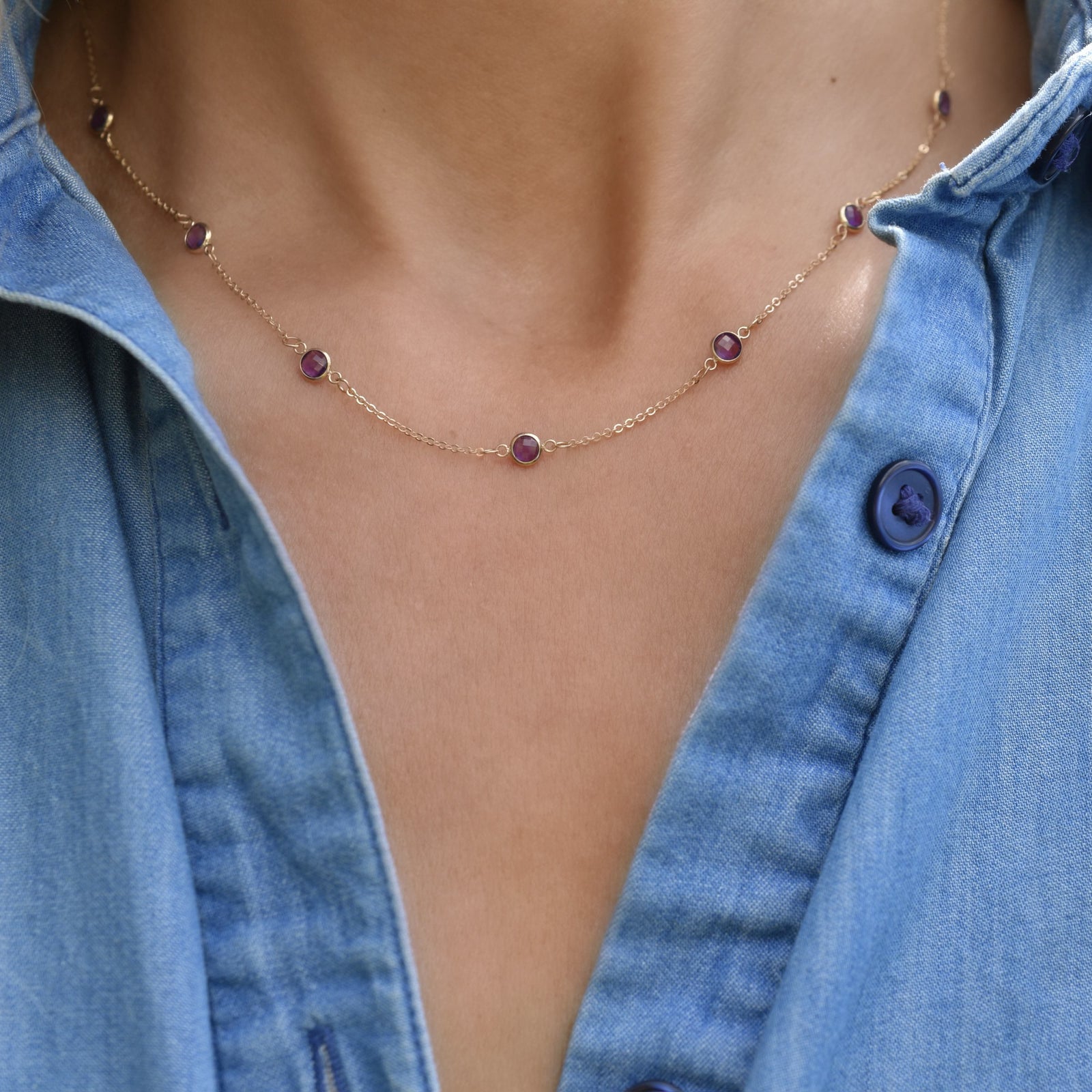 Woman wearing a Bayberry 11 Birthstone necklace featuring 4 mm briolette amethysts bezel set in 14k yellow gold