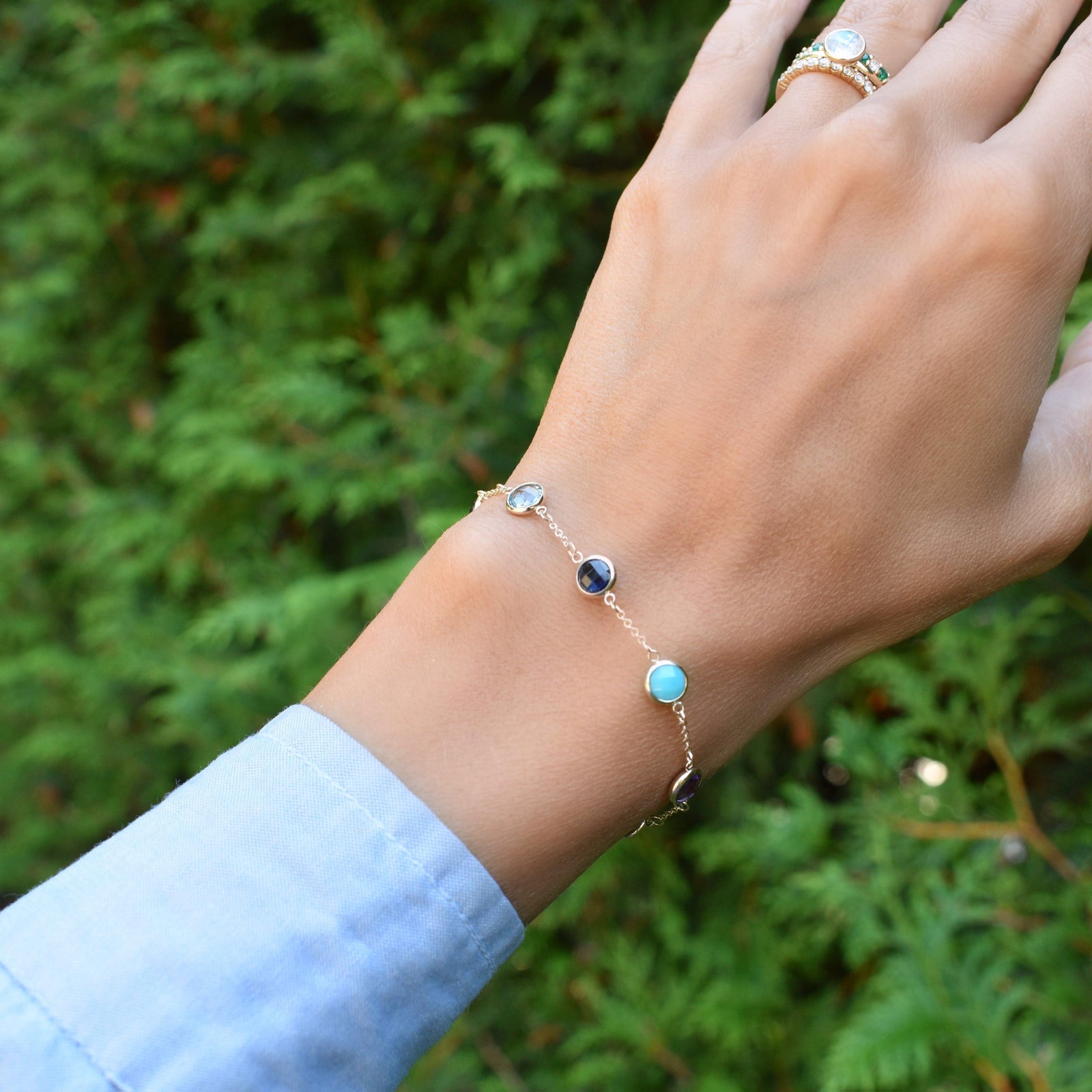 Woman wearing a gold Grand 1.17 mm cable chain bracelet featuring 6 mm briolette cut bezel set gemstones