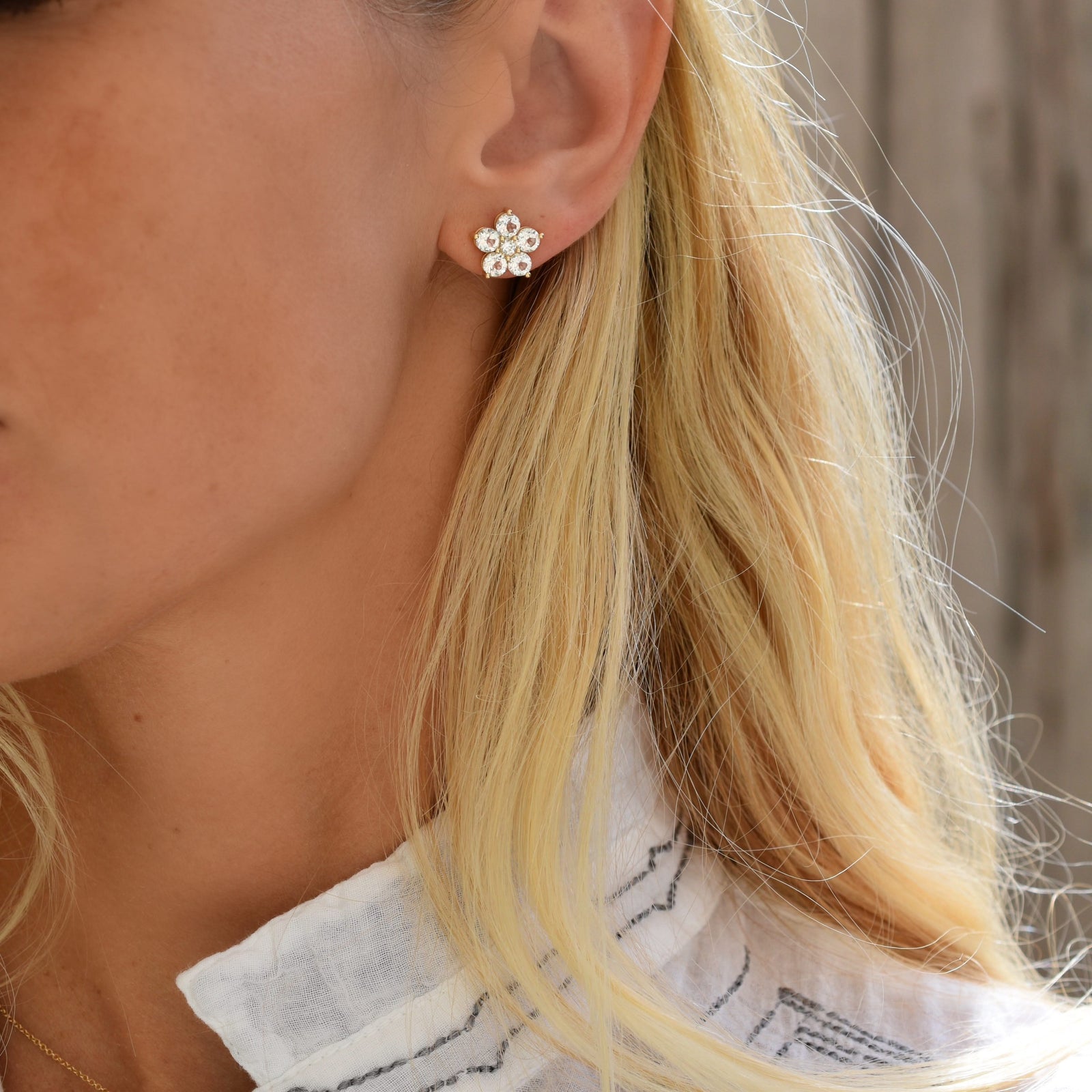 Woman with a 14k yellow gold Greenwich 5 Birthstone earring featuring five 4 mm round cut white topaz and one 2.1 mm diamond