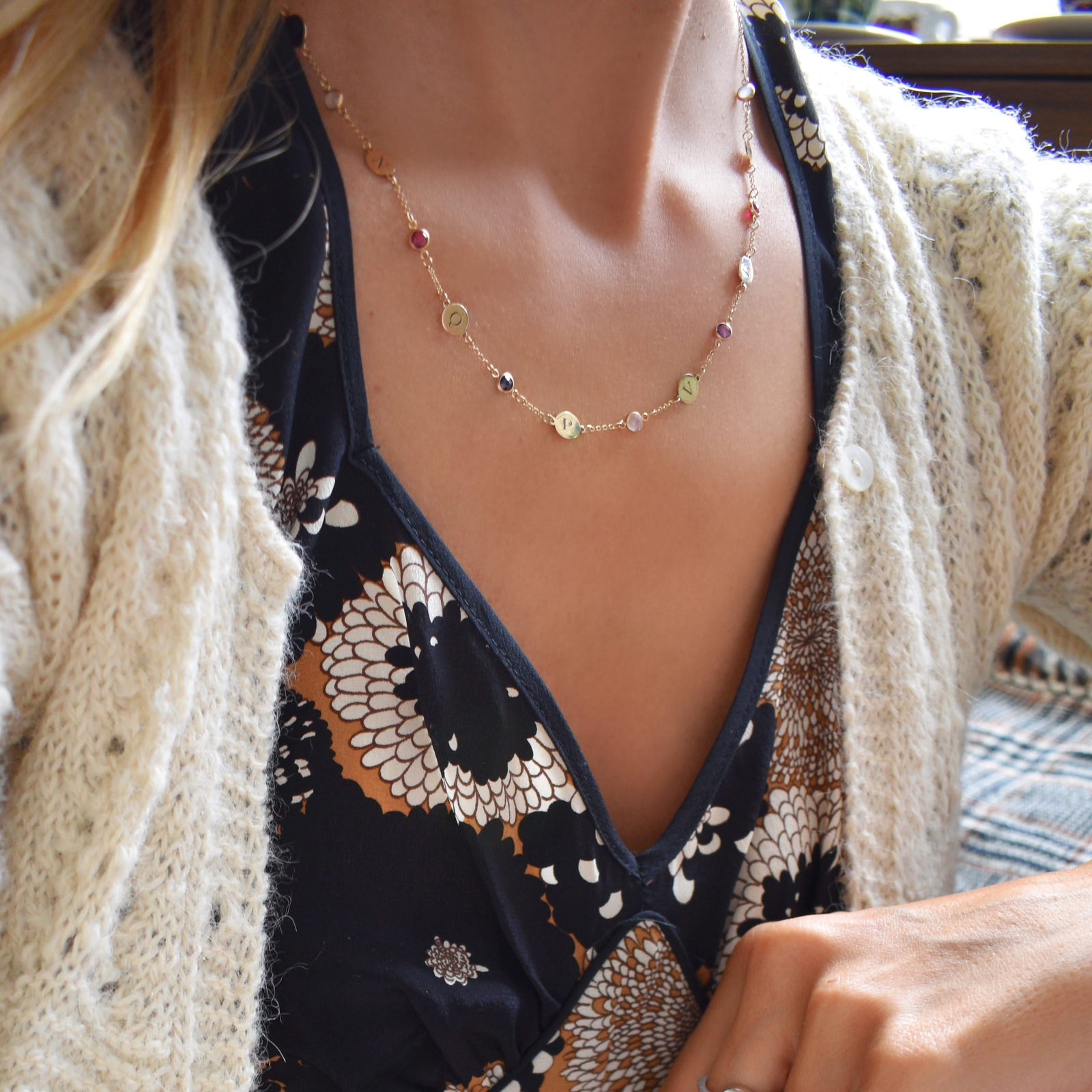 Woman with a 14k yellow gold Classic necklace featuring 10 birthstones and 10 flat discs engraved with letters