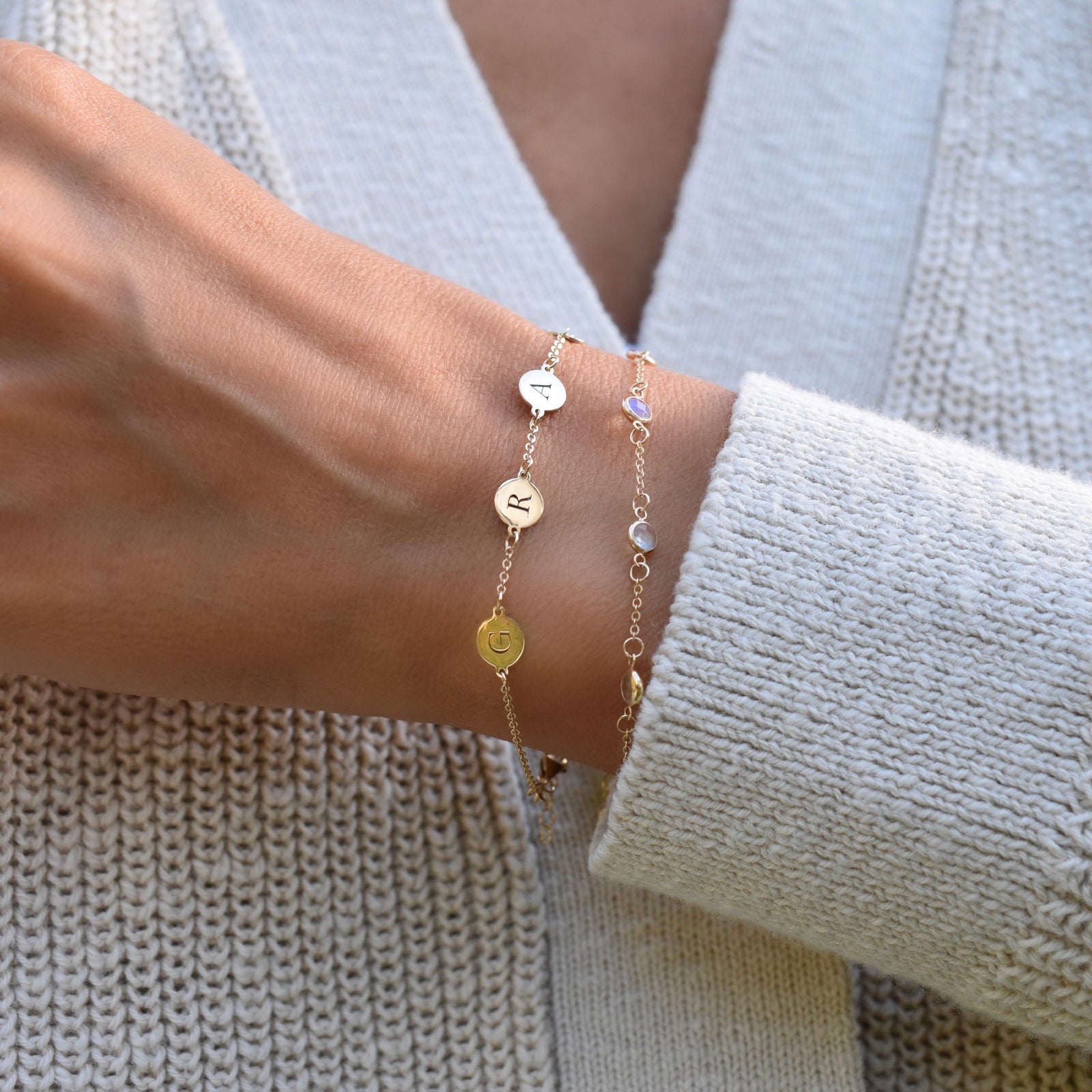 Woman wearing a 14k yellow gold cable chain bracelet featuring 1/4” flat engraved letter discs