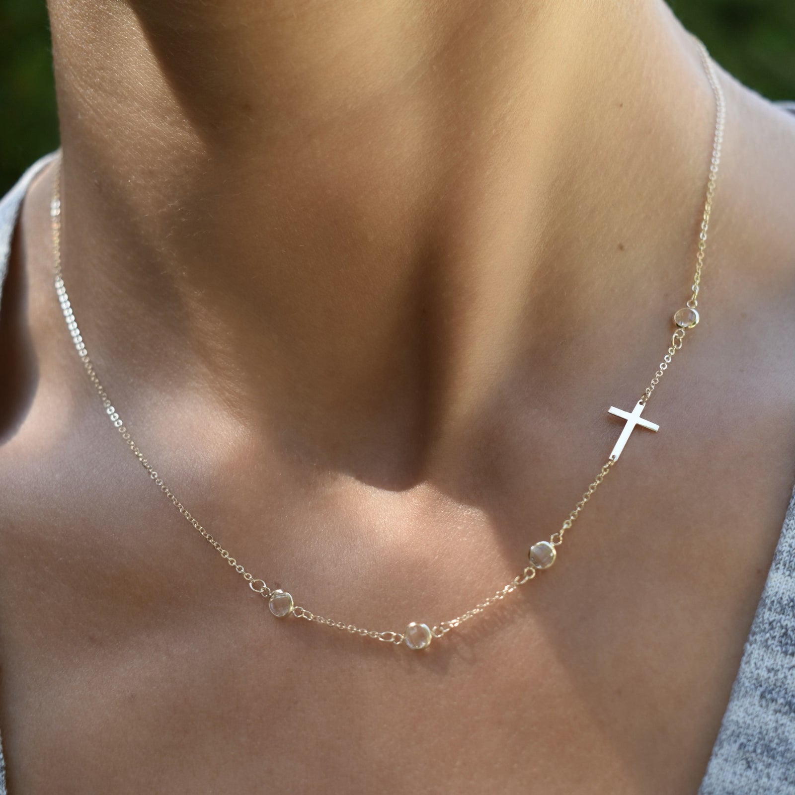 Woman with a 14k yellow gold 1.17 mm cable chain necklace featuring four round birthstones and a 1/2" cutout cross