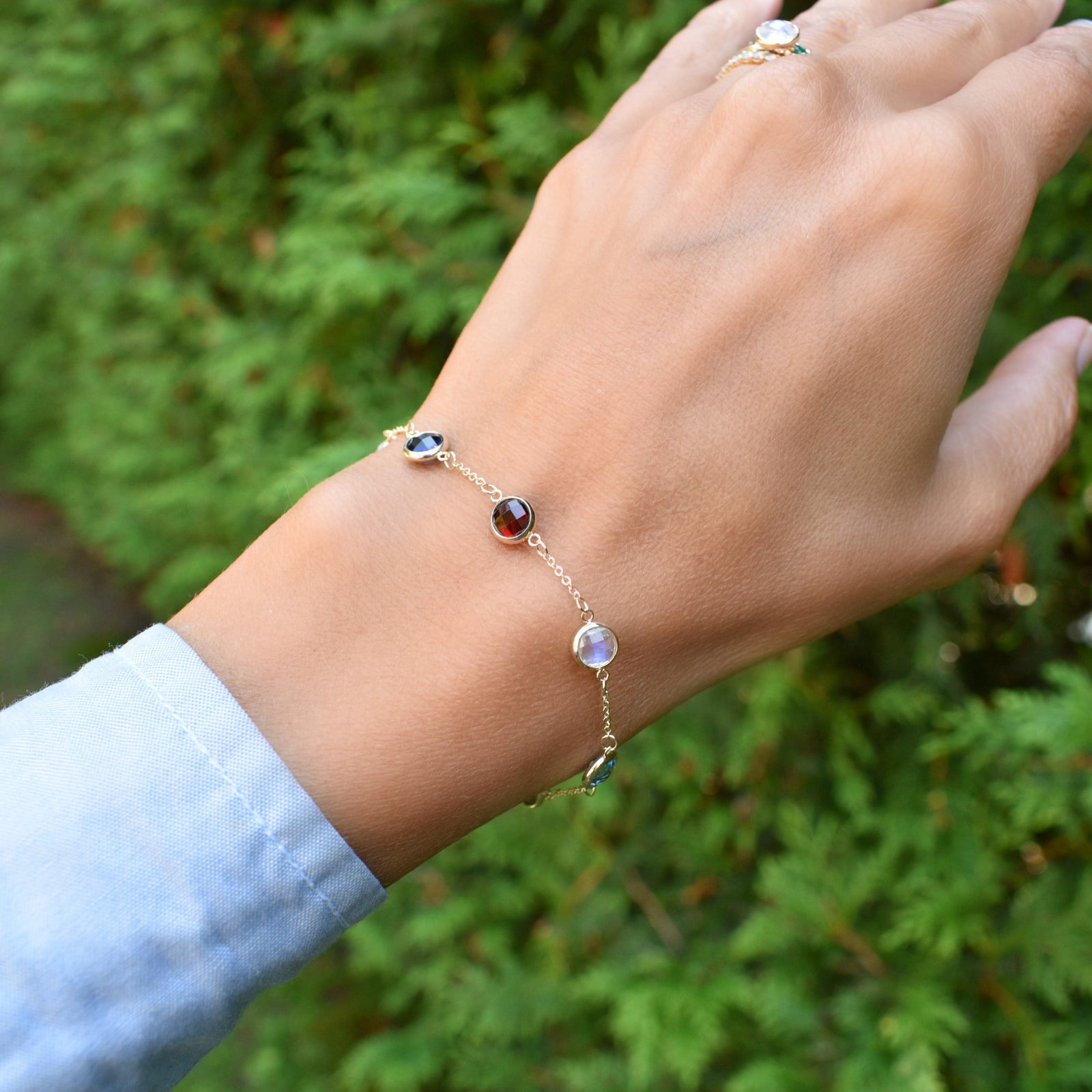 Woman wearing a Grand 14k yellow gold bracelet featuring 6 mm briolette cut bezel set gemstones