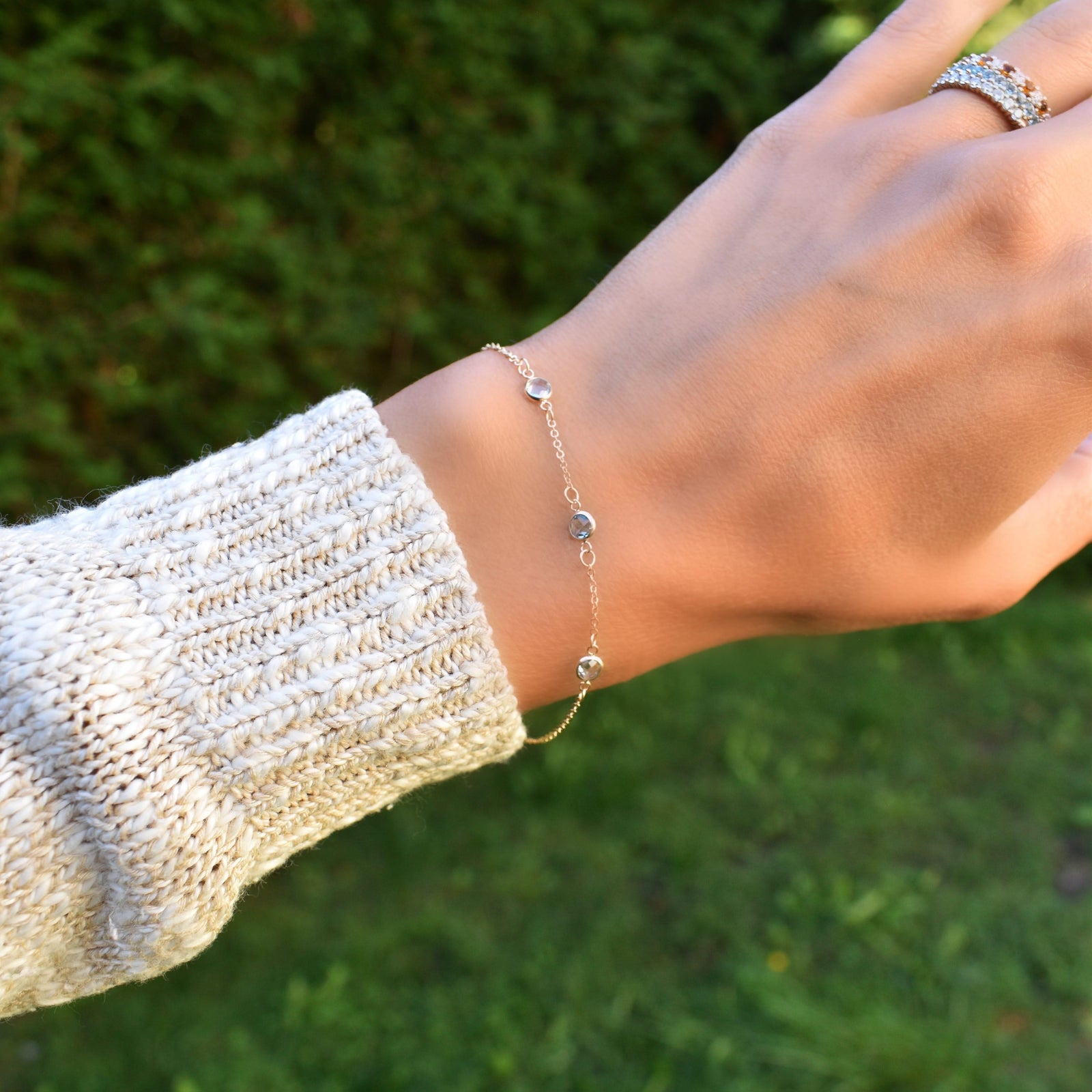 Woman wearing a Bayberry cable chain birthstone bracelet featuring three 4 mm Nantucket blue topaz bezel set in 14k gold
