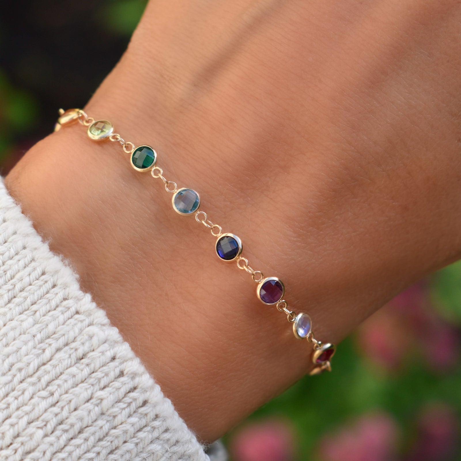 Woman with a Newport 14k yellow gold bracelet featuring 4 mm briolette cut bezel set rainbow hued gemstones