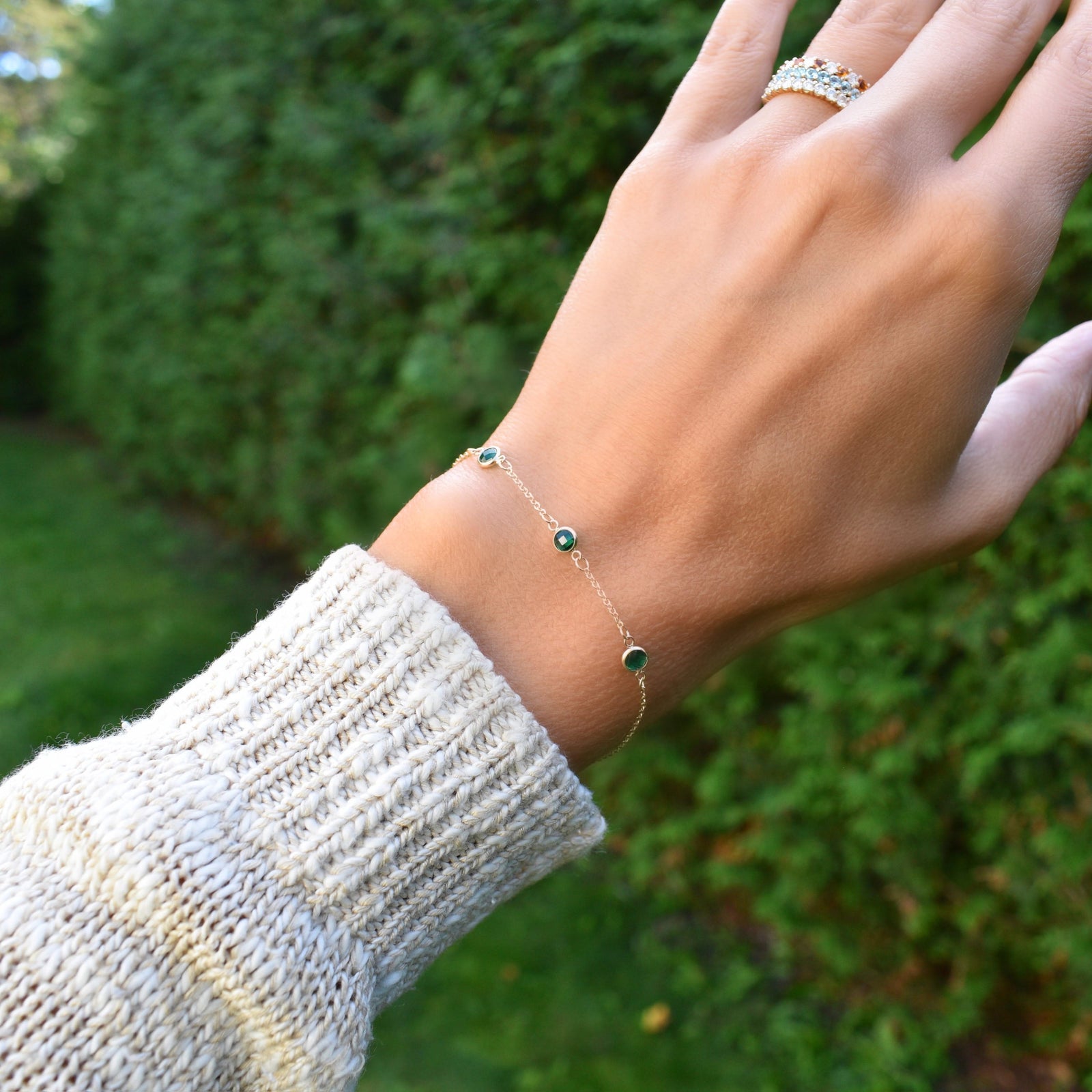 Woman wearing a Bayberry cable chain birthstone bracelet featuring three 4 mm briolette emeralds bezel set in 14k gold