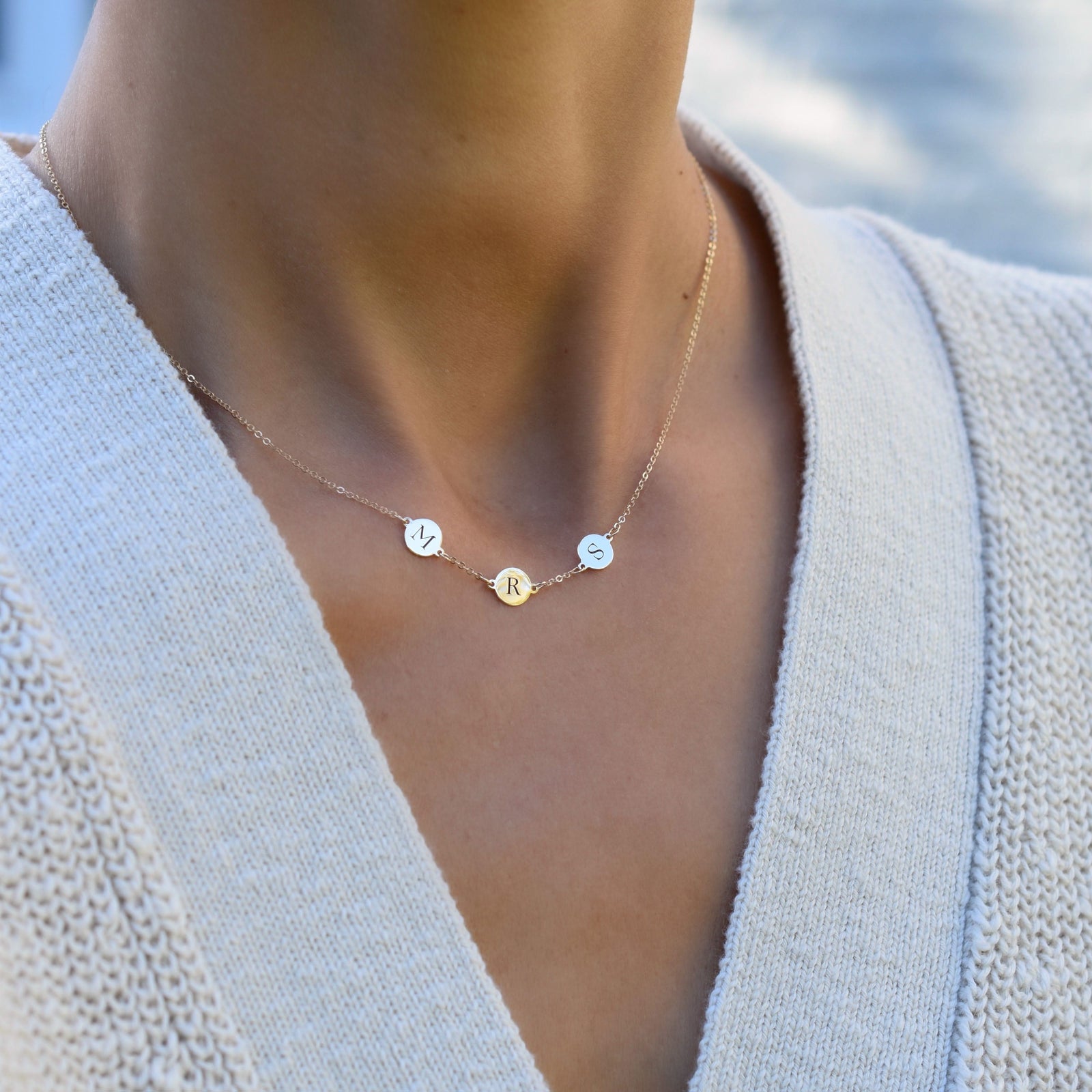Woman wearing a 14k yellow gold cable chain necklace featuring three 1/4” flat engraved letter discs, spelling Mrs