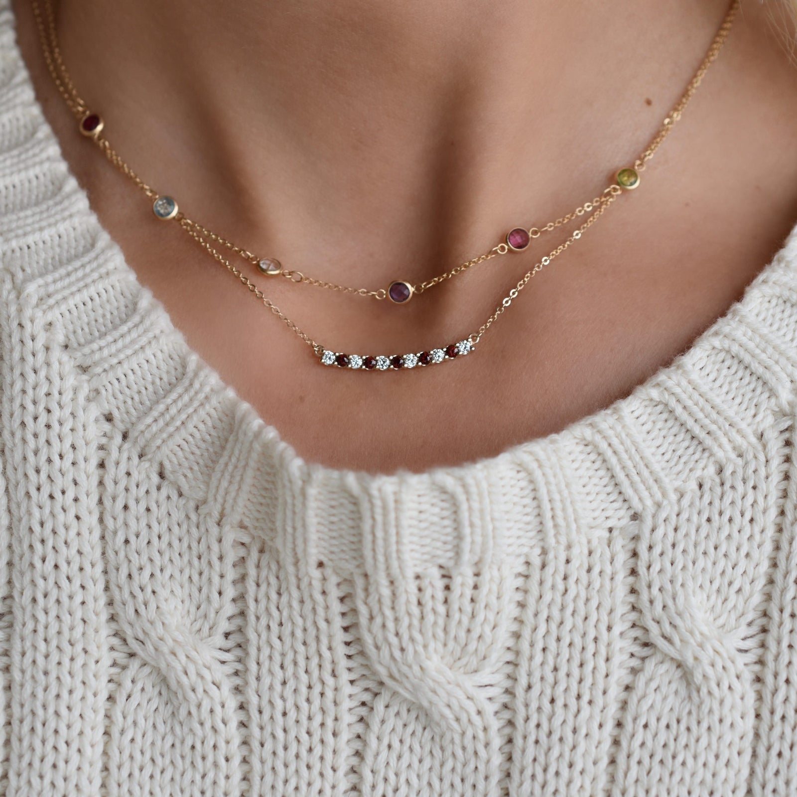 Woman wearing two gold necklaces including a Rosecliff bar necklace with eleven alternating 2 mm garnets and diamonds