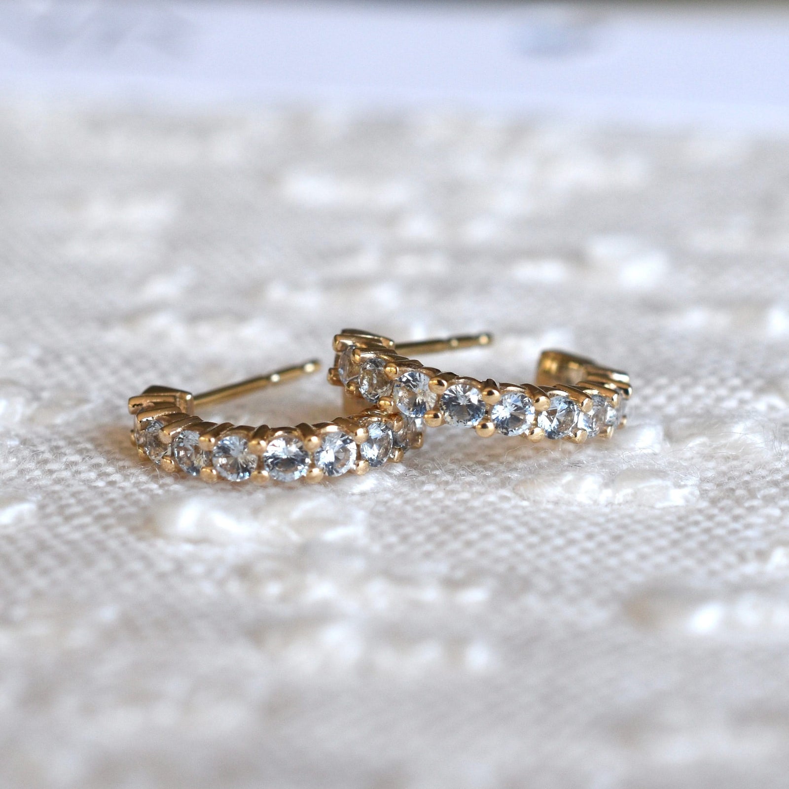 A pair of Rosecliff huggie earrings in 14k yellow gold featuring nine 2mm faceted round cut prong set aquamarines