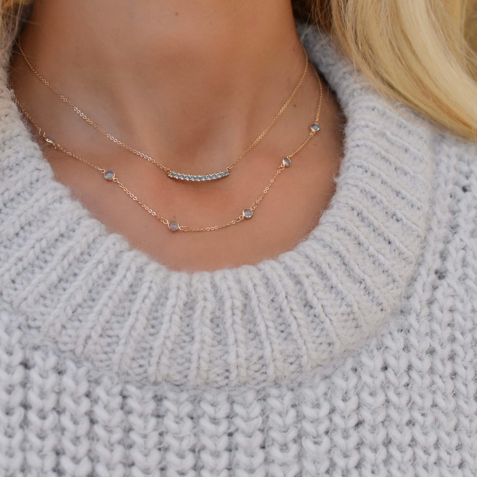 Woman wearing two necklaces including a Rosecliff bar necklace with eleven Nantucket blue topaz prong set in solid 14k gold