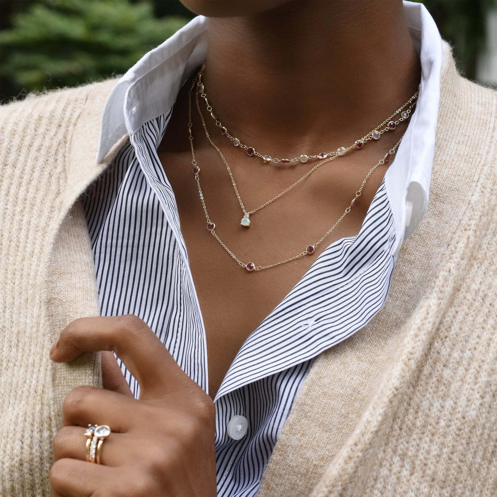 Woman with layered necklaces including a Greenwich necklace featuring one 4 mm round cut opal and one 2.1 mm diamond