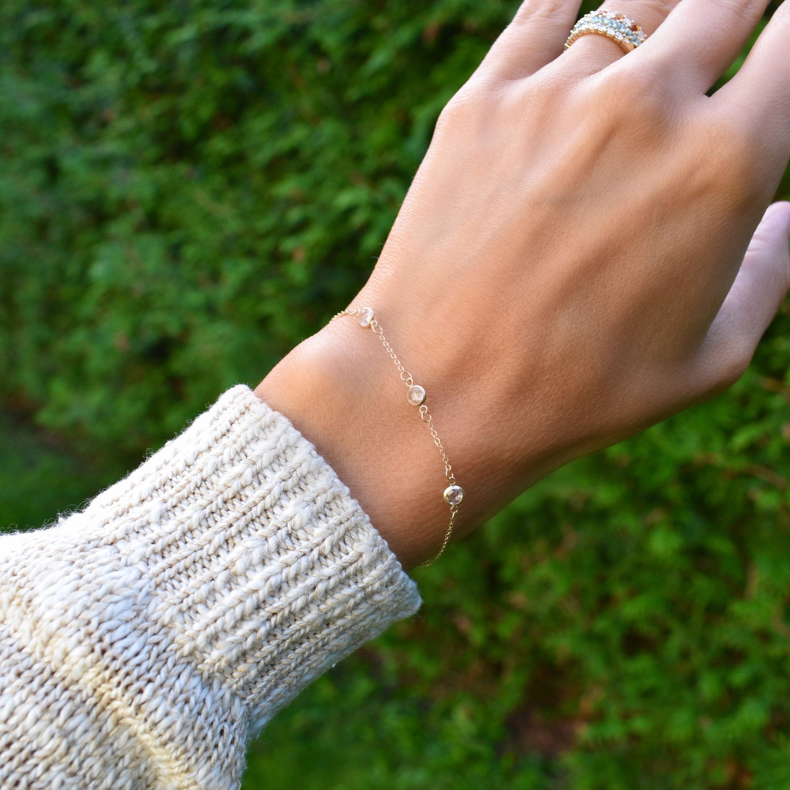 Woman wearing a Bayberry cable chain birthstone bracelet featuring three 4 mm briolette white topaz bezel set in 14k gold