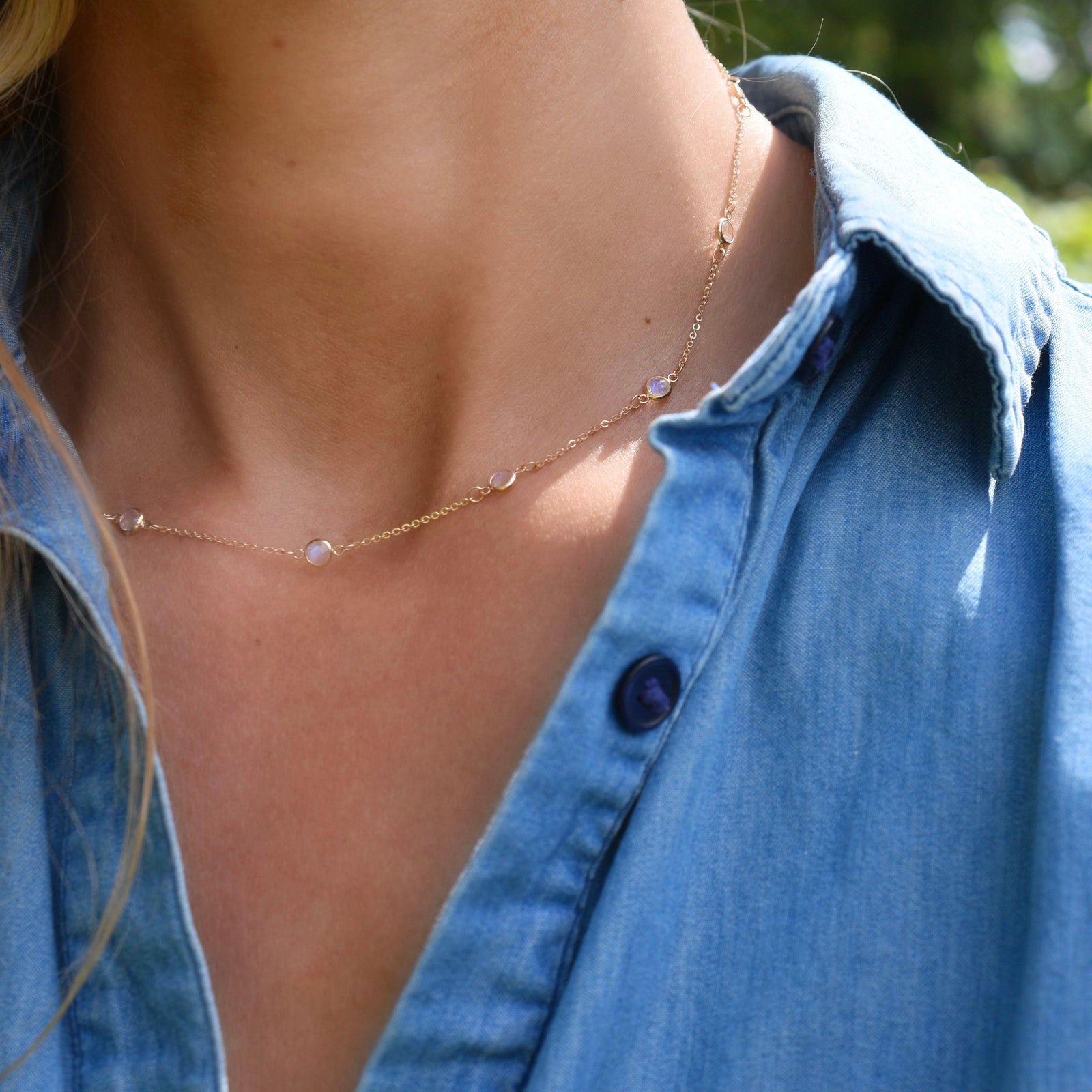 Woman wearing a Bayberry 11 Birthstone necklace featuring 4 mm briolette moonstones bezel set in 14k yellow gold