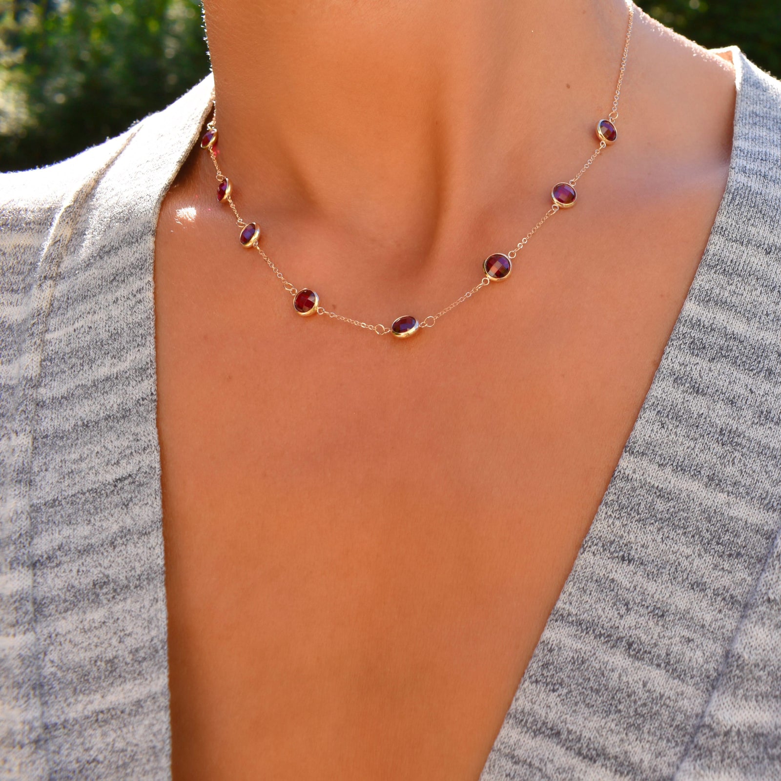 Woman wearing a Grand 14k yellow gold necklace featuring eight 6 mm briolette cut bezel set gemstones