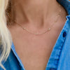 Woman wearing a Bayberry 11 Birthstone necklace featuring 4 mm briolette white topaz bezel set in 14k gold
