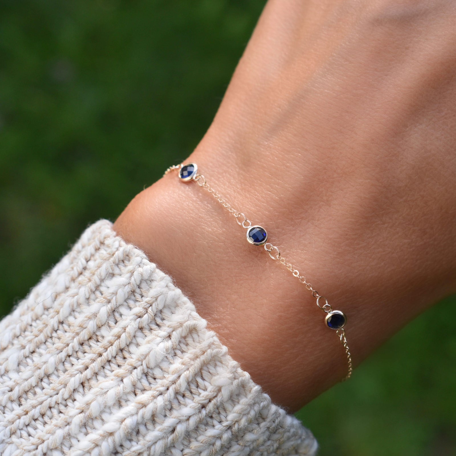 Woman with a Bayberry cable chain birthstone bracelet featuring three 4 mm briolette sapphires bezel set in 14k yellow gold