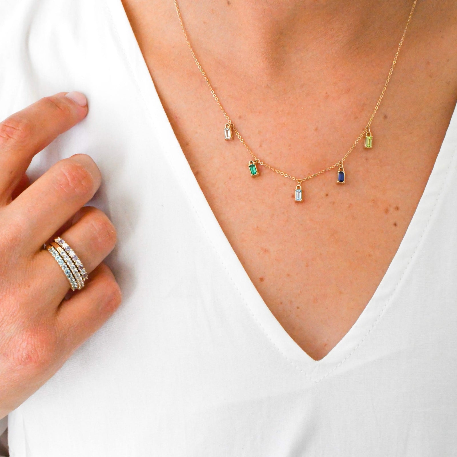 Woman wearing a personalized Providence 5 birthstone drop necklace and 3 Rosecliff birthstone stackable rings