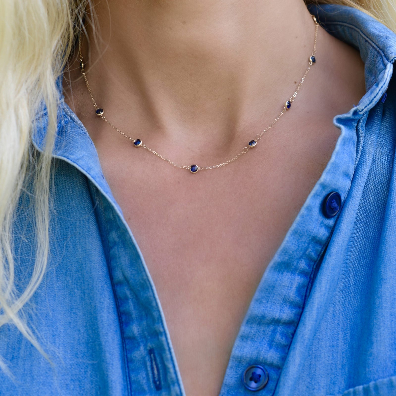 Woman wearing a Bayberry 11 Birthstone necklace featuring 4 mm briolette sapphires bezel set in 14k gold