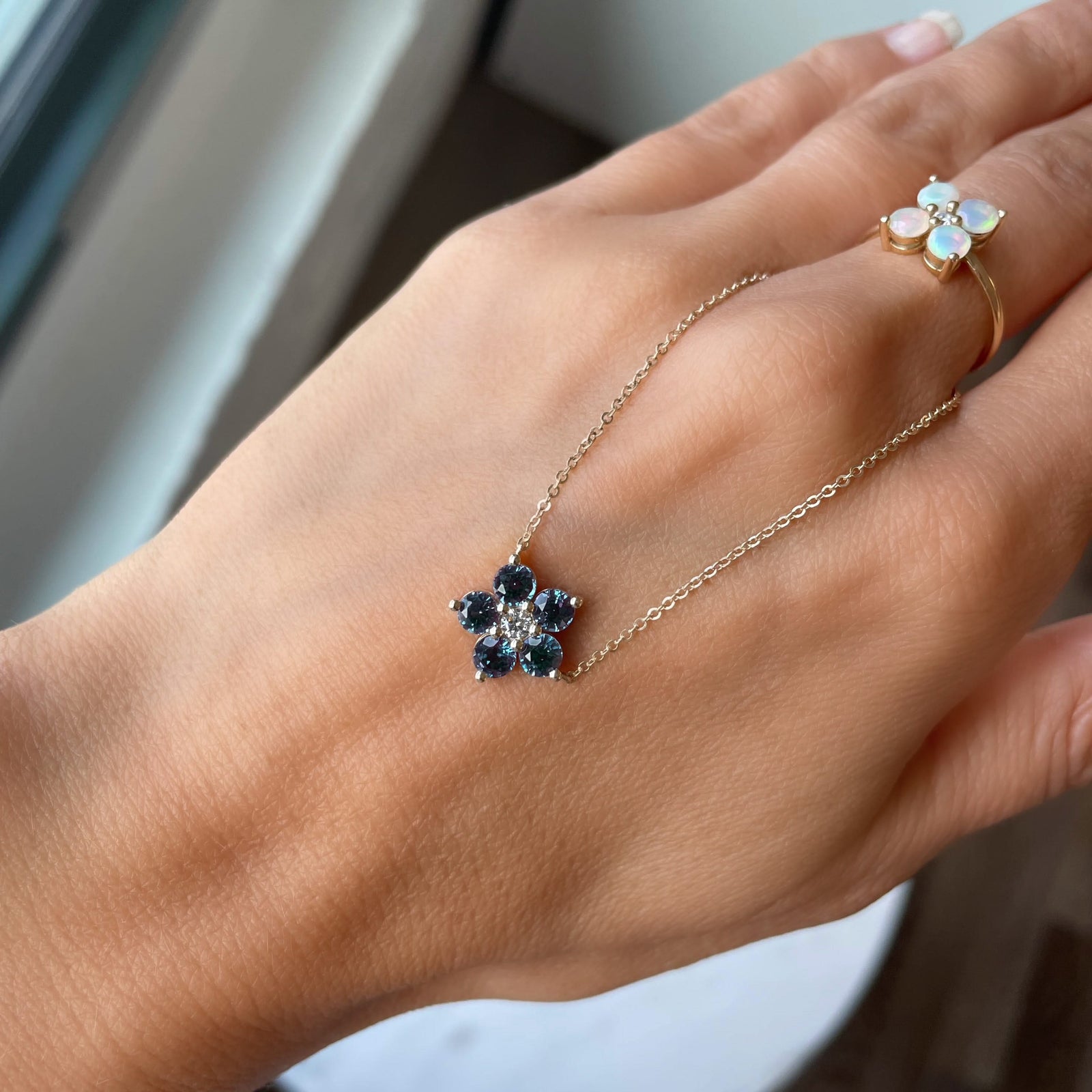 Woman holding a Greenwich cable chain necklace featuring five 4 mm alexandrites & one 2.1 mm diamond bezel set in 14k gold