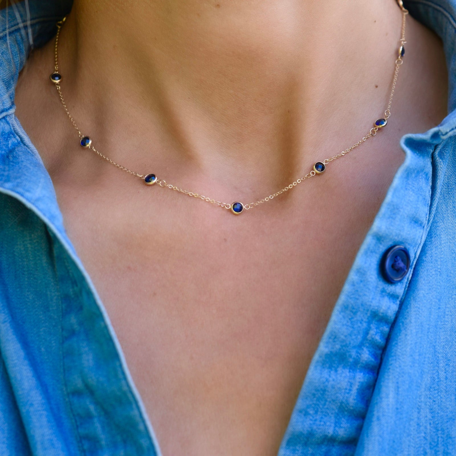 Woman wearing a Bayberry 11 Birthstone necklace featuring 4 mm briolette sapphires bezel set in 14k yellow gold