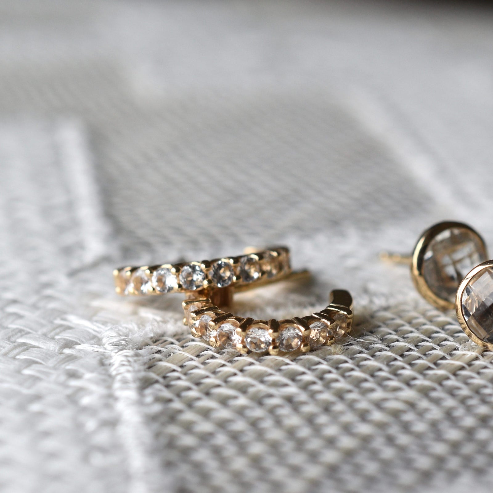 Two pairs of earrings including Rosecliff huggie earrings in 14k gold each featuring nine 2mm faceted round cut white topaz