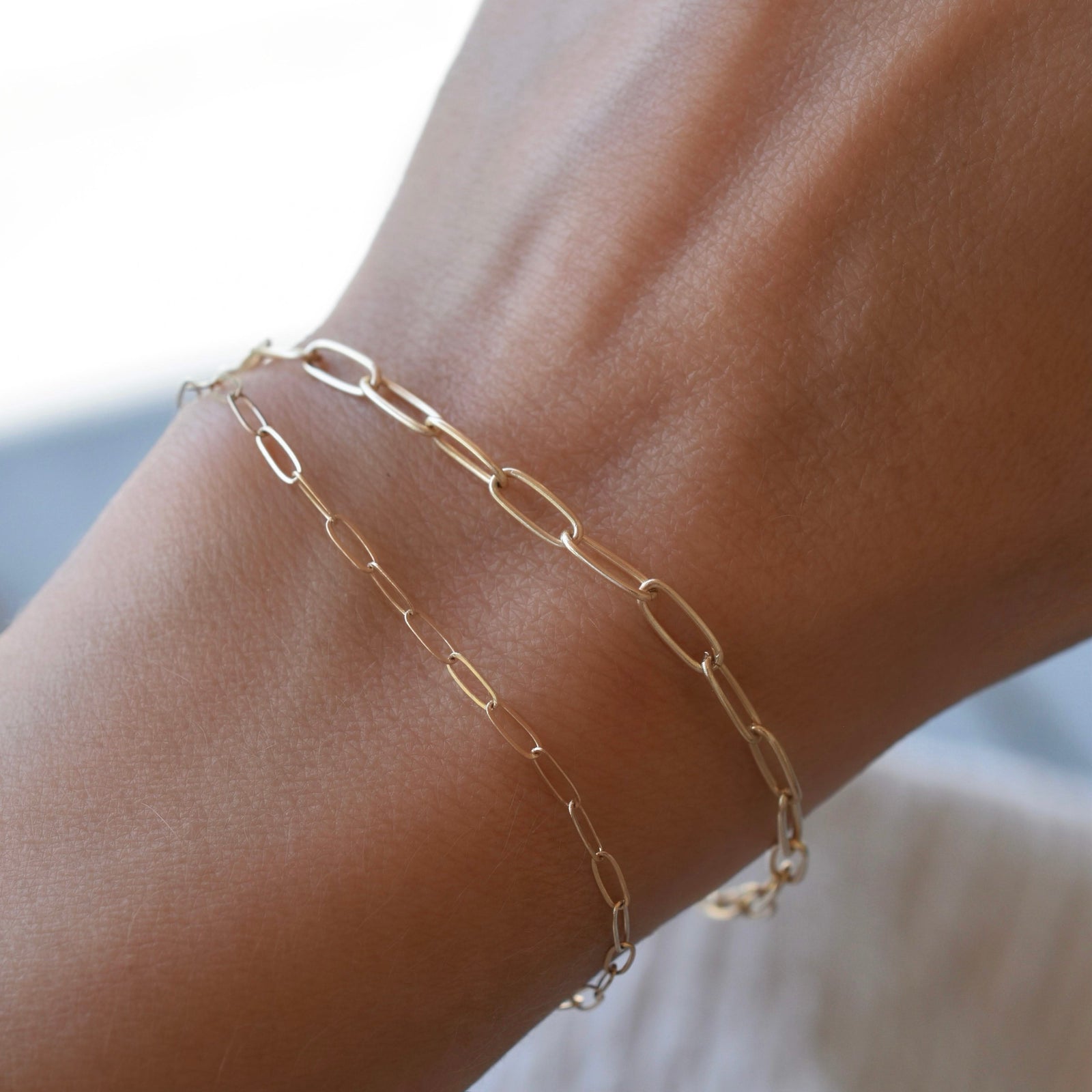 Woman wearing two Adelaide bracelets featuring paperclip chain links