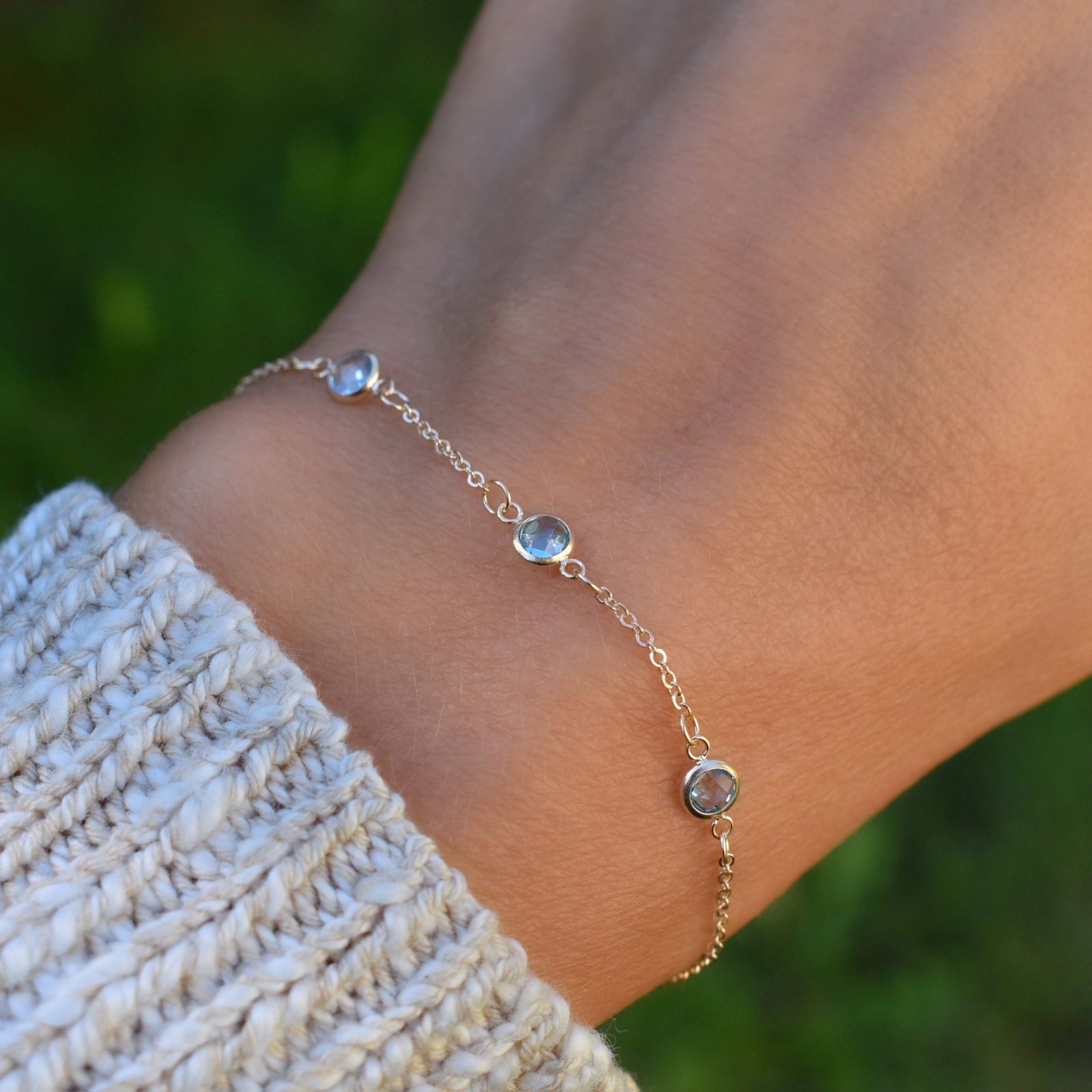 Woman with a Bayberry cable chain birthstone bracelet featuring three 4 mm Nantucket blue topaz bezel set in 14k yellow gold