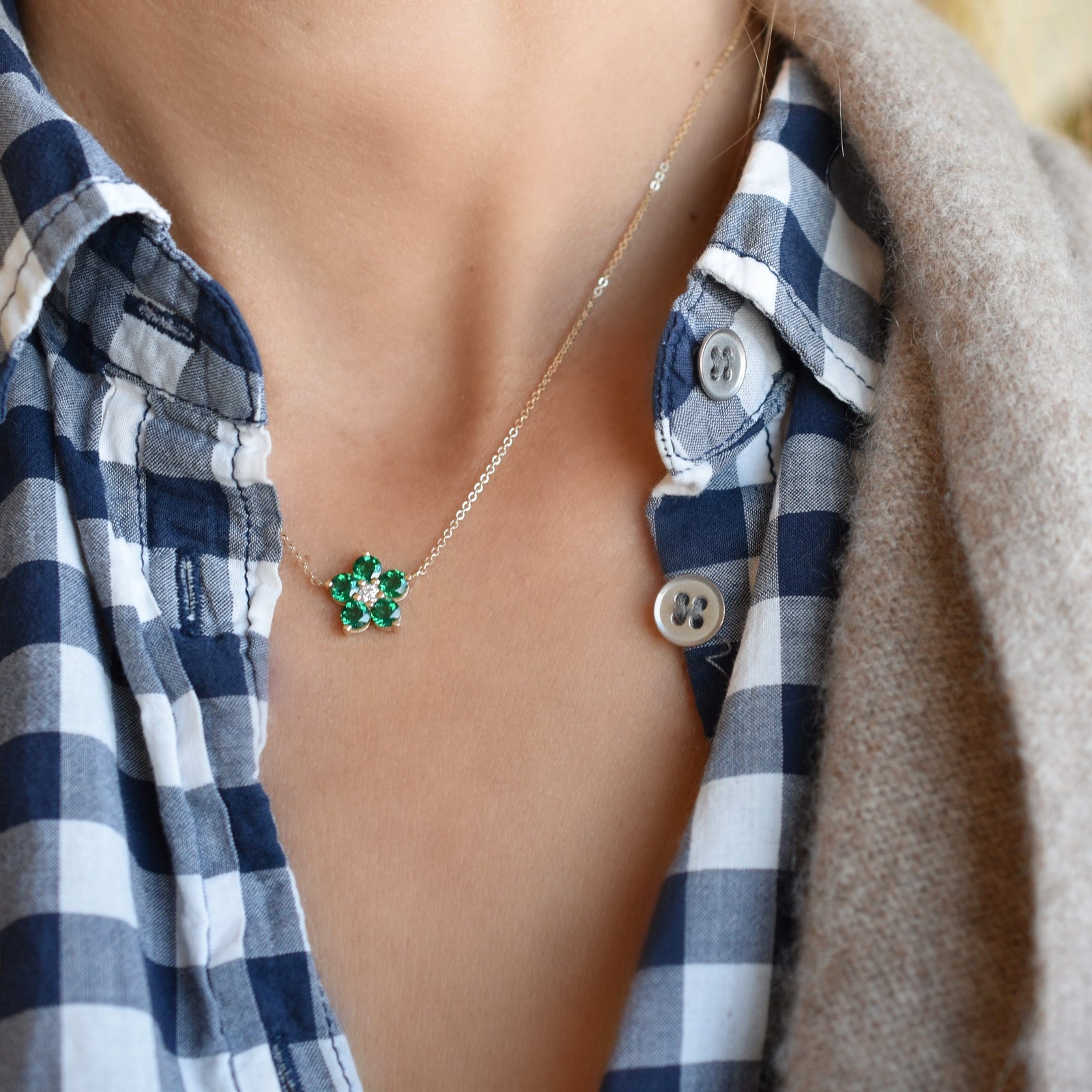 Woman with a Greenwich cable chain necklace featuring five 4 mm faceted emeralds and one 2.1 mm diamond bezel set in 14k gold