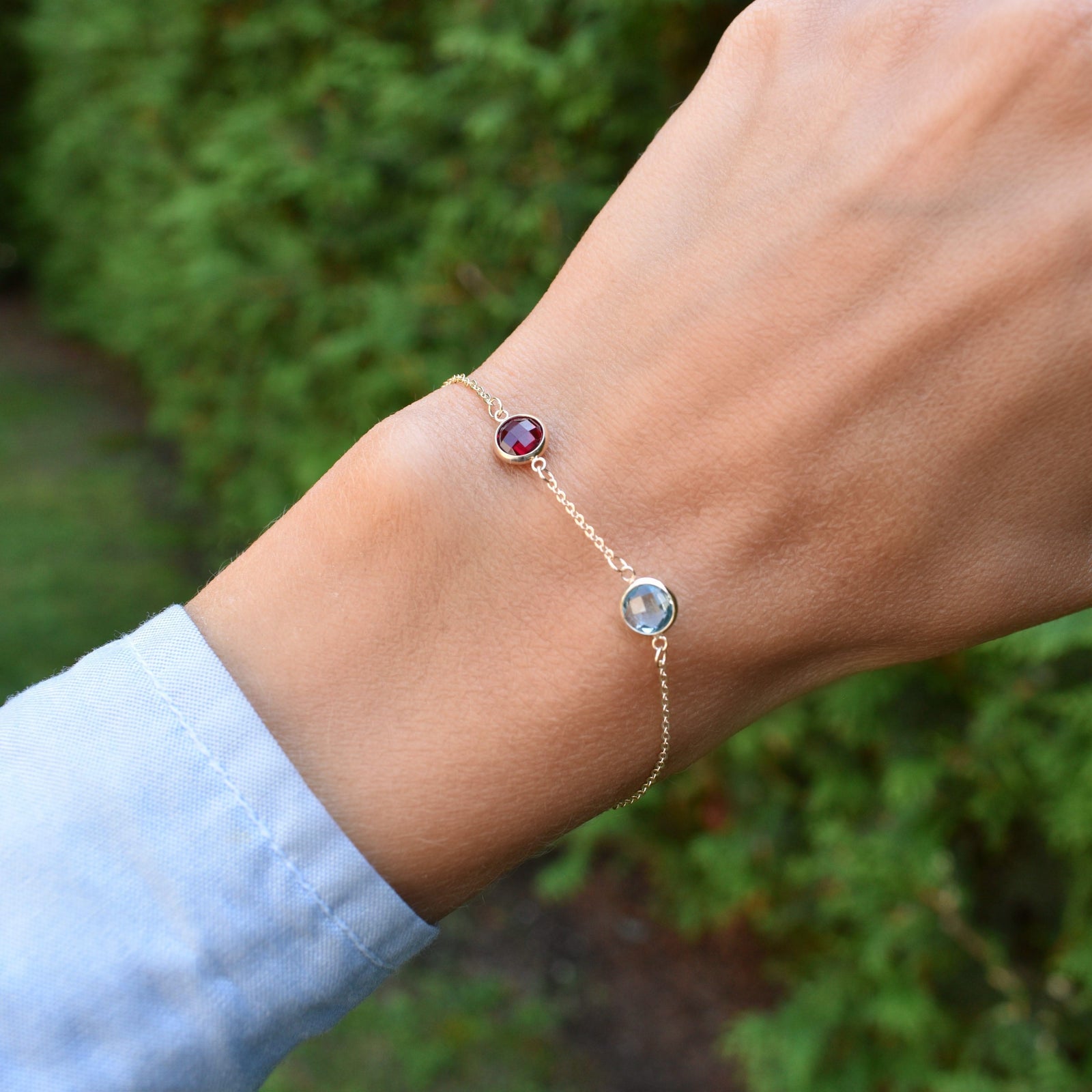 Woman wearing a 2 Grand 1.17 mm cable chain bracelet in 14k gold featuring two 6 mm briolette cut bezel set gemstones