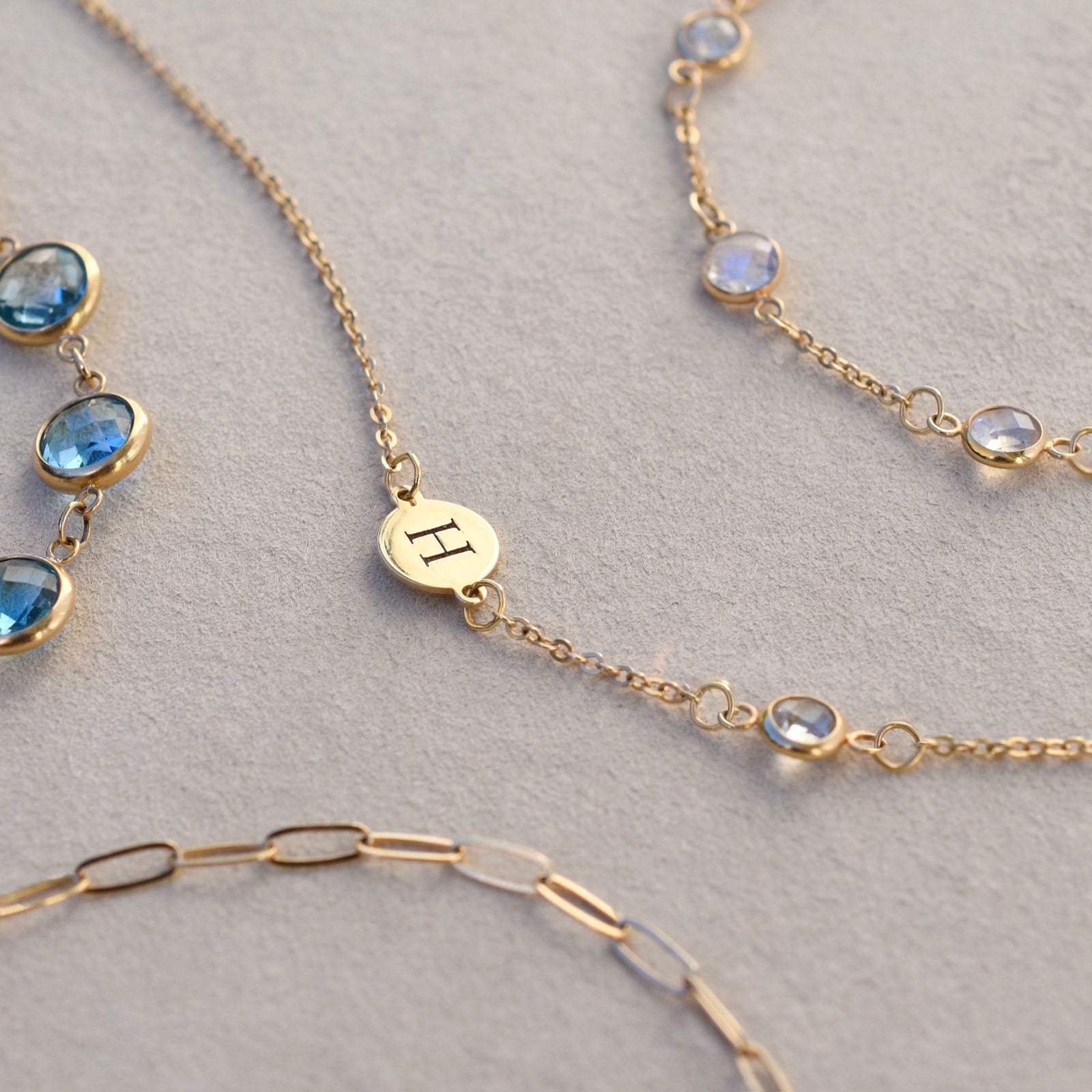 Bracelets including a 14k gold Classic bracelet featuring one amethyst and one 1/4” flat disc engraved with the letter H