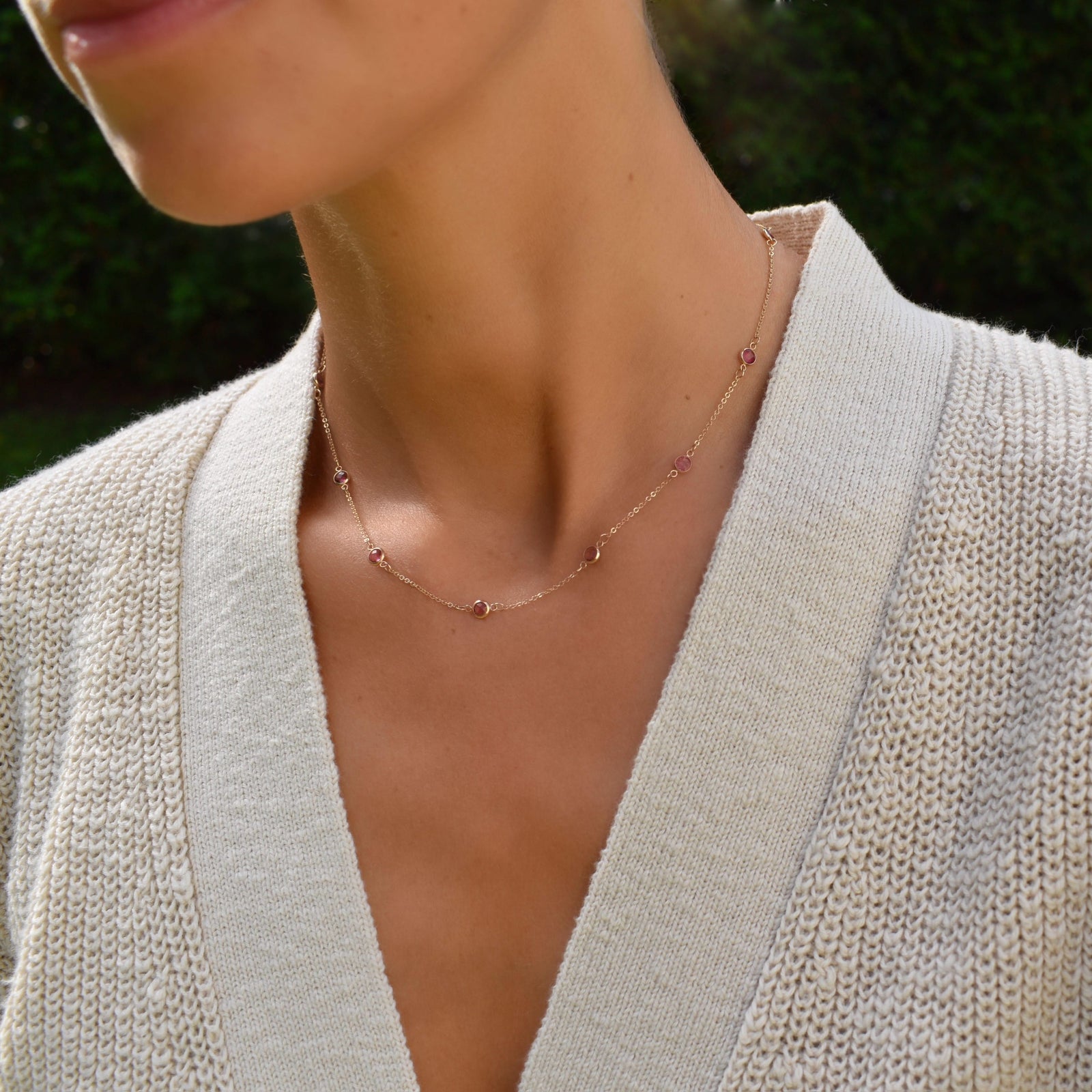 Woman wearing a Bayberry 11 Birthstone necklace featuring 4 mm briolette pink tourmalines bezel set in 14k gold