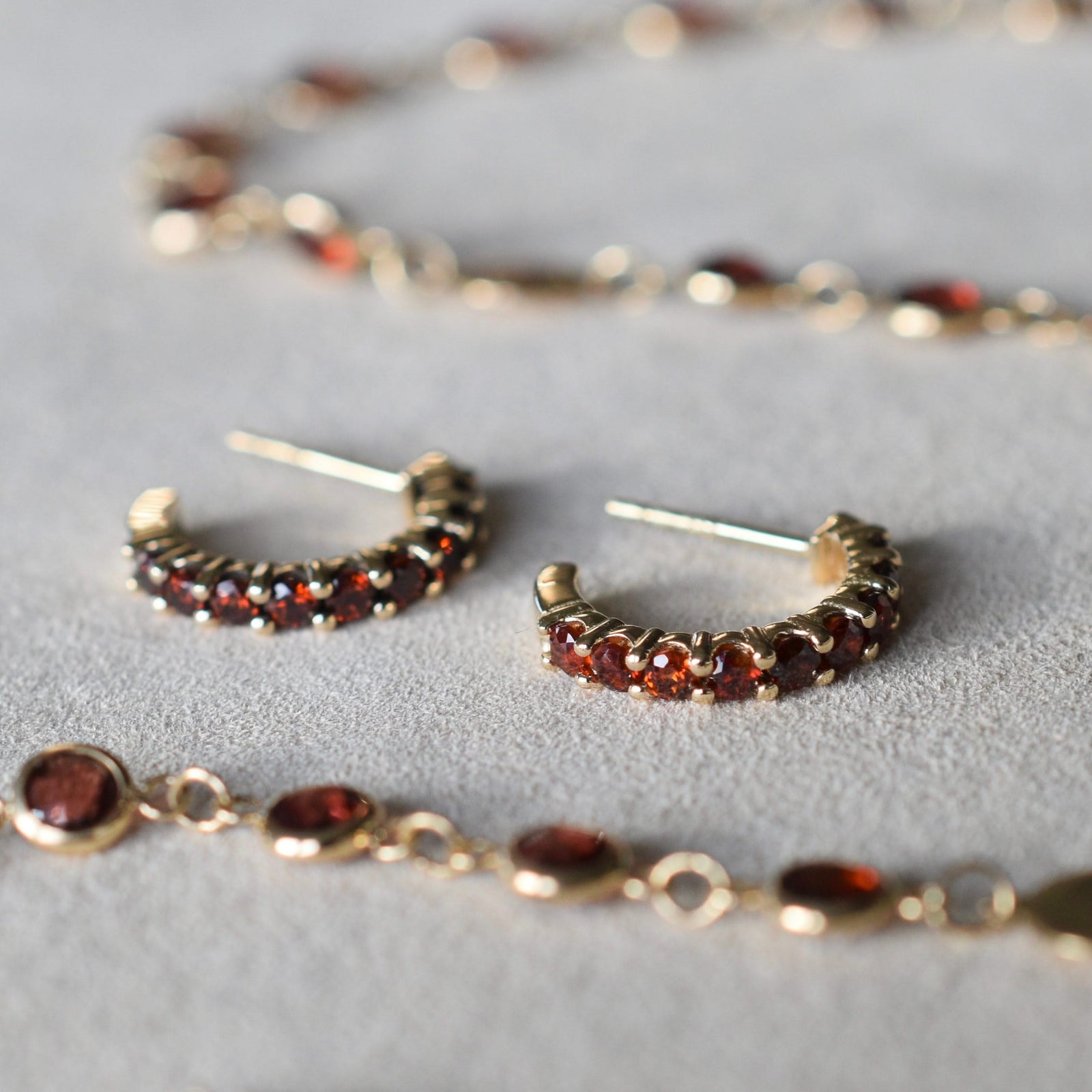 A Newport necklace and a pair of Rosecliff huggie earrings in 14k yellow gold featuring nine 2mm round cut garnets each