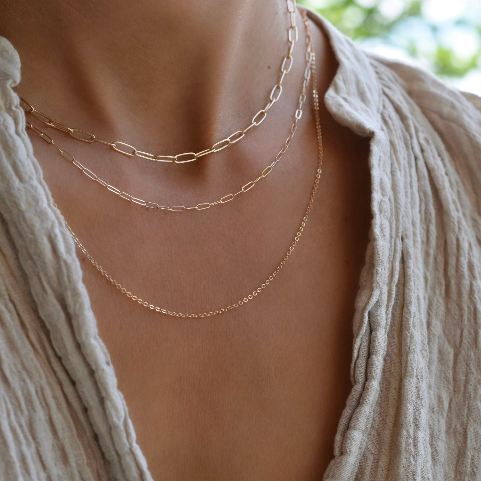 Woman wearing layered necklaces including a 14k gold Adelaide mini necklace featuring 8.4 x 3 mm paperclip chain links