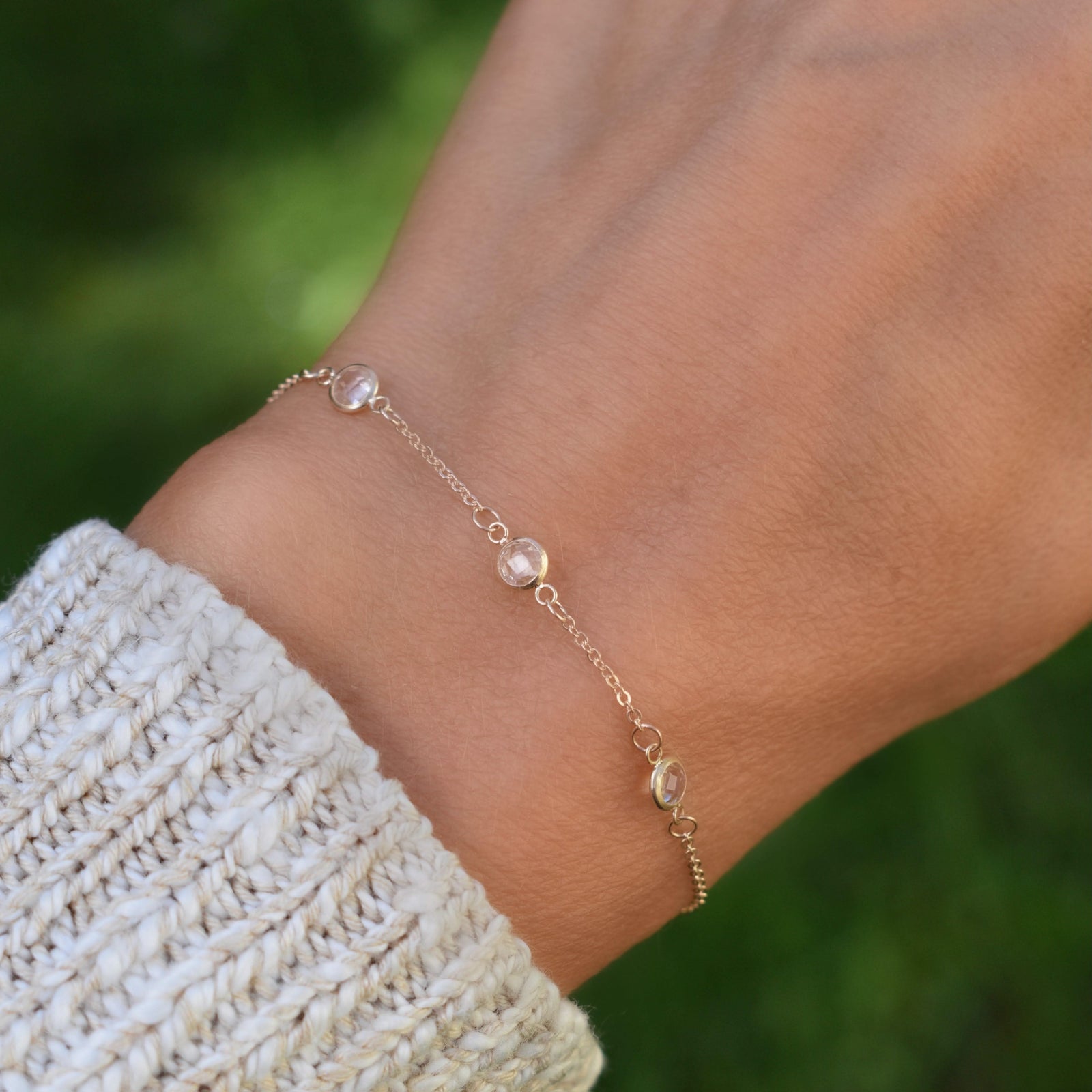 Woman with a Bayberry cable chain birthstone bracelet featuring three 4 mm briolette white topaz bezel set in 14k yellow gold