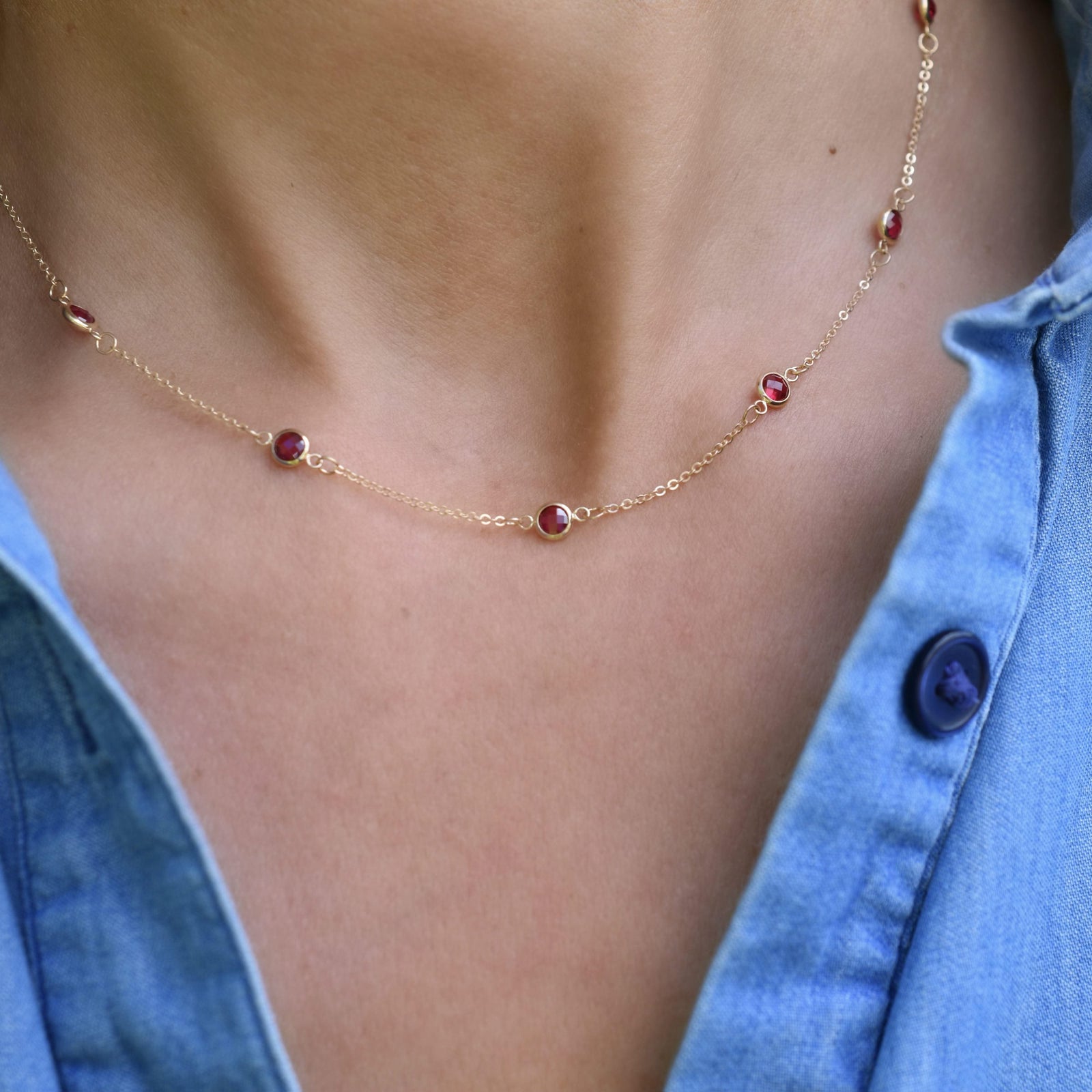 Woman wearing a Bayberry 11 Birthstone necklace featuring 4 mm briolette rubies bezel set in 14k yellow gold