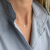 Woman wearing a 14k yellow gold Solidarity necklace featuring a 1/4” flat disc engraved with a sunflower