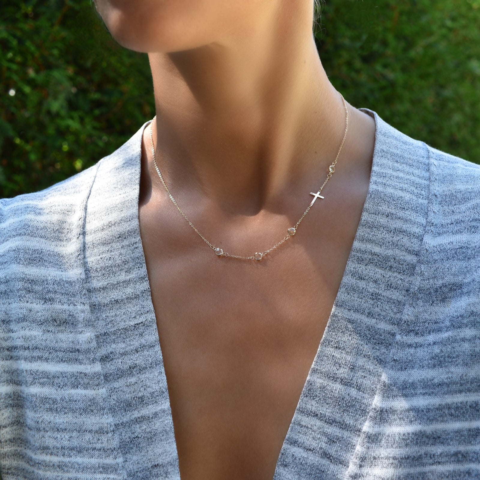 Woman wearing a 14k yellow gold 1.17 mm cable chain necklace featuring four round birthstones and a 1/2" cutout cross