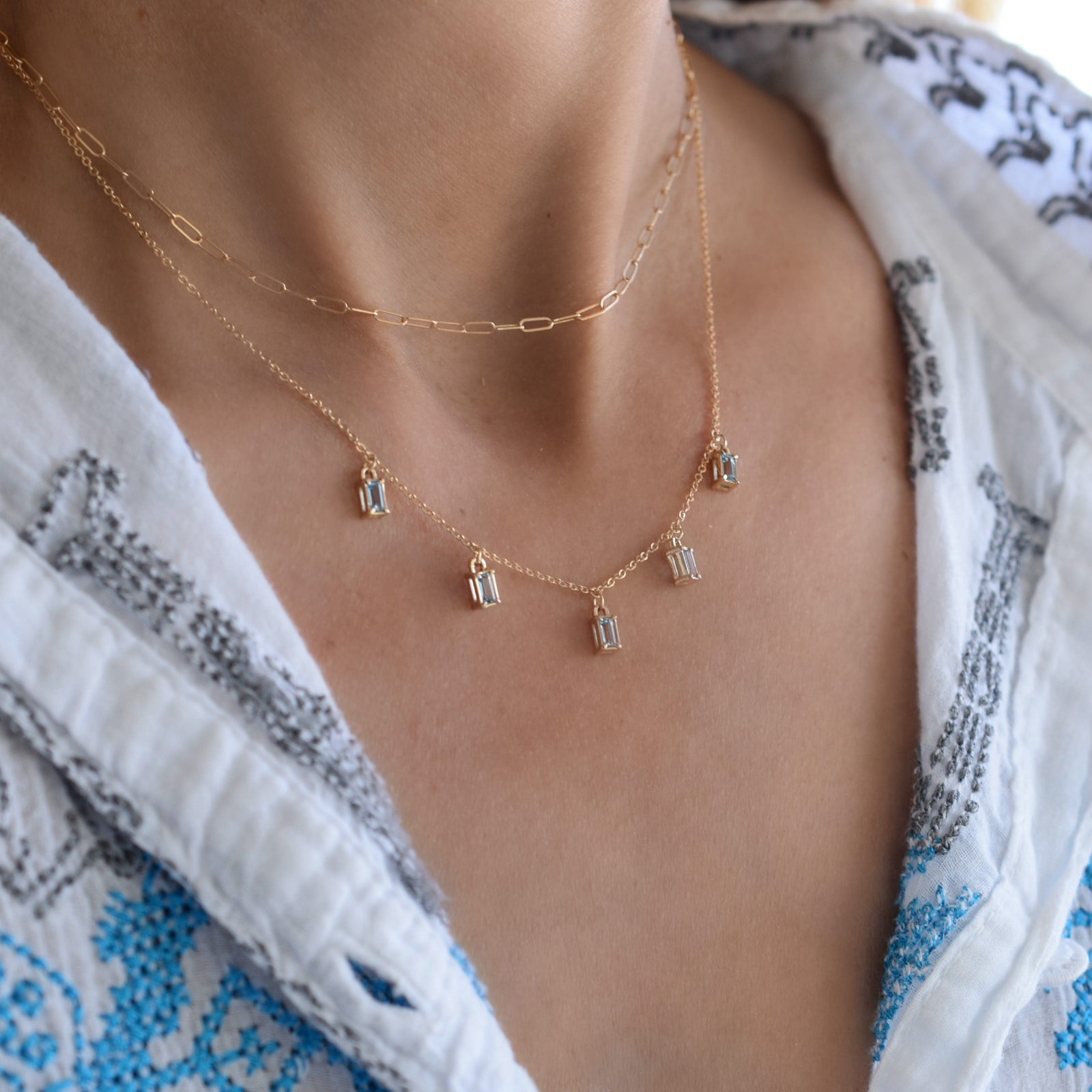 Woman wearing a Providence 5 Nantucket Blue Topaz drop necklace with petite baguette cut stones set in 14k yellow gold