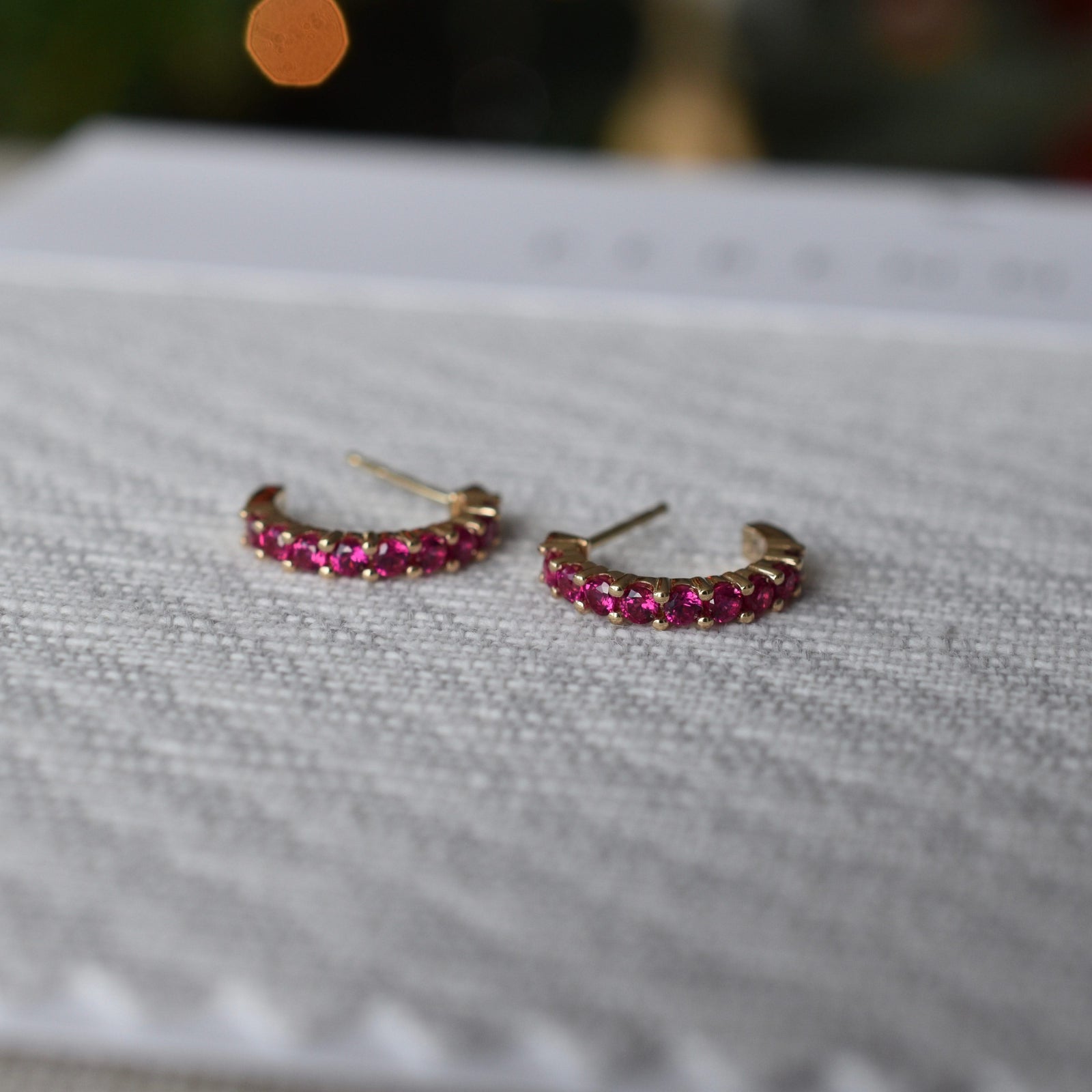 A pair of Rosecliff huggie earrings in 14k yellow gold each featuring nine 2mm faceted round cut prong set rubies