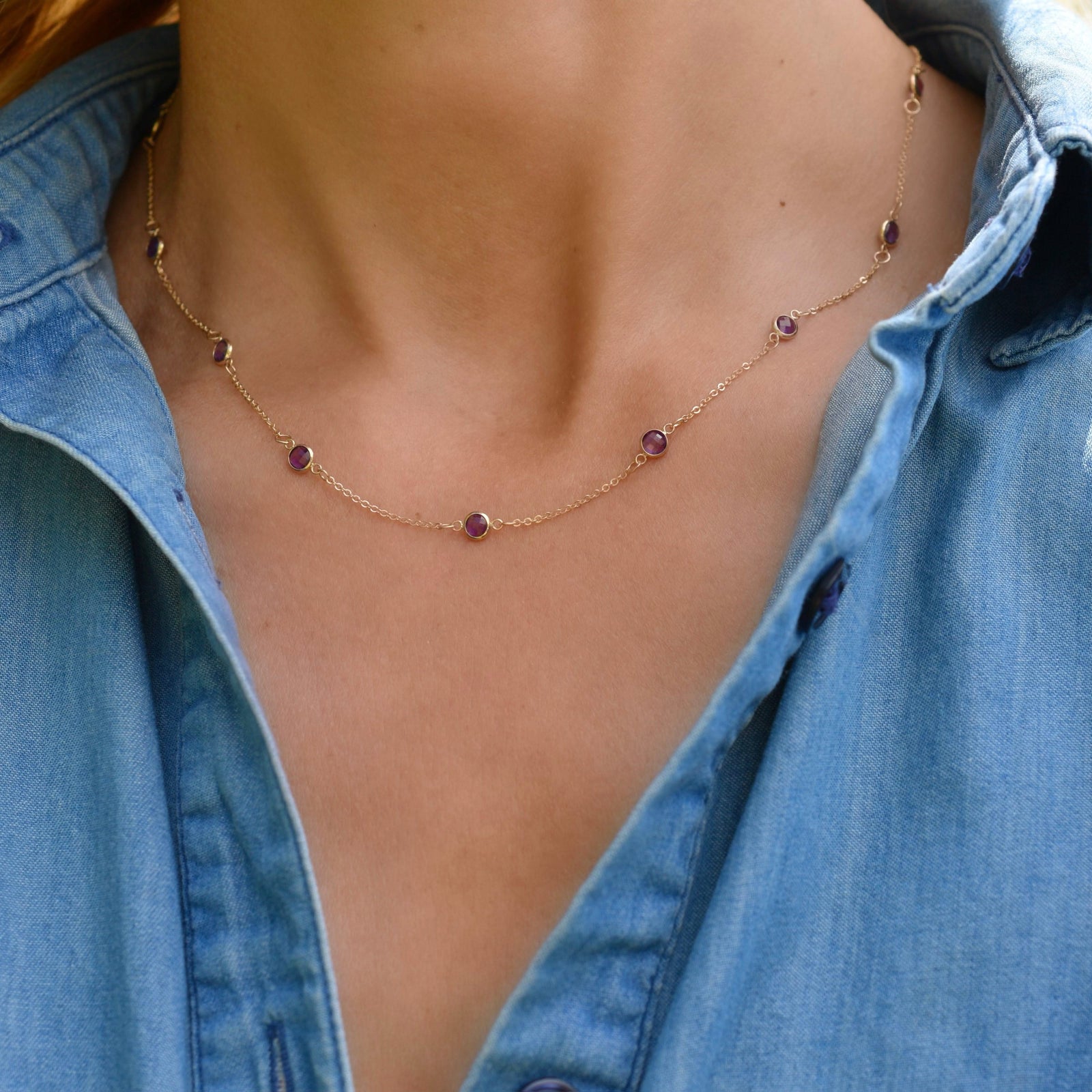 Woman wearing a Bayberry 11 Birthstone necklace featuring 4 mm briolette amethysts bezel set in 14k gold