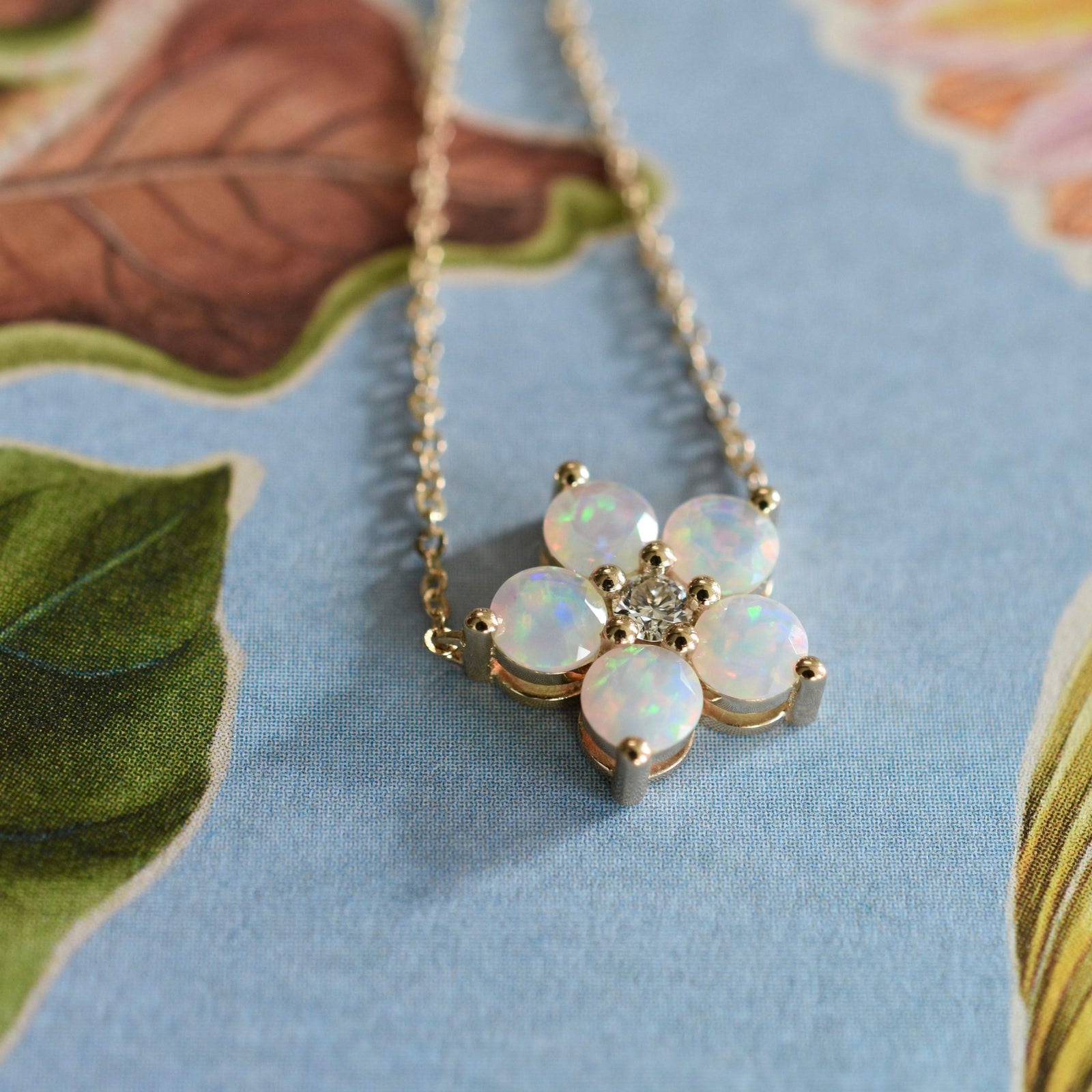 Greenwich cable chain necklace featuring five 4 mm round cut opals and one 2.1 mm diamond bezel set in 14k gold