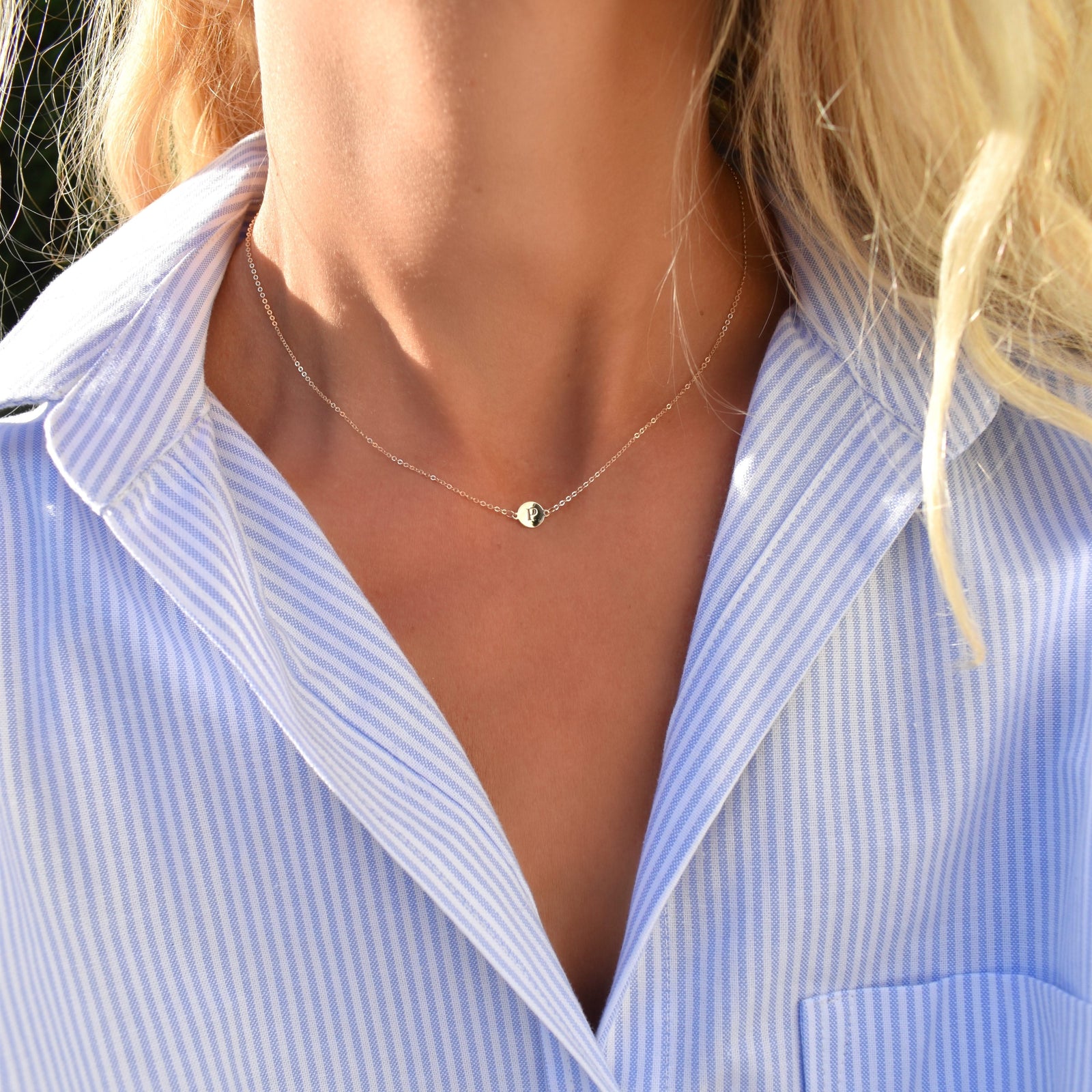 Woman wearing a 14k yellow gold cable chain necklace featuring one 1/4” flat disc engraved with the letter P