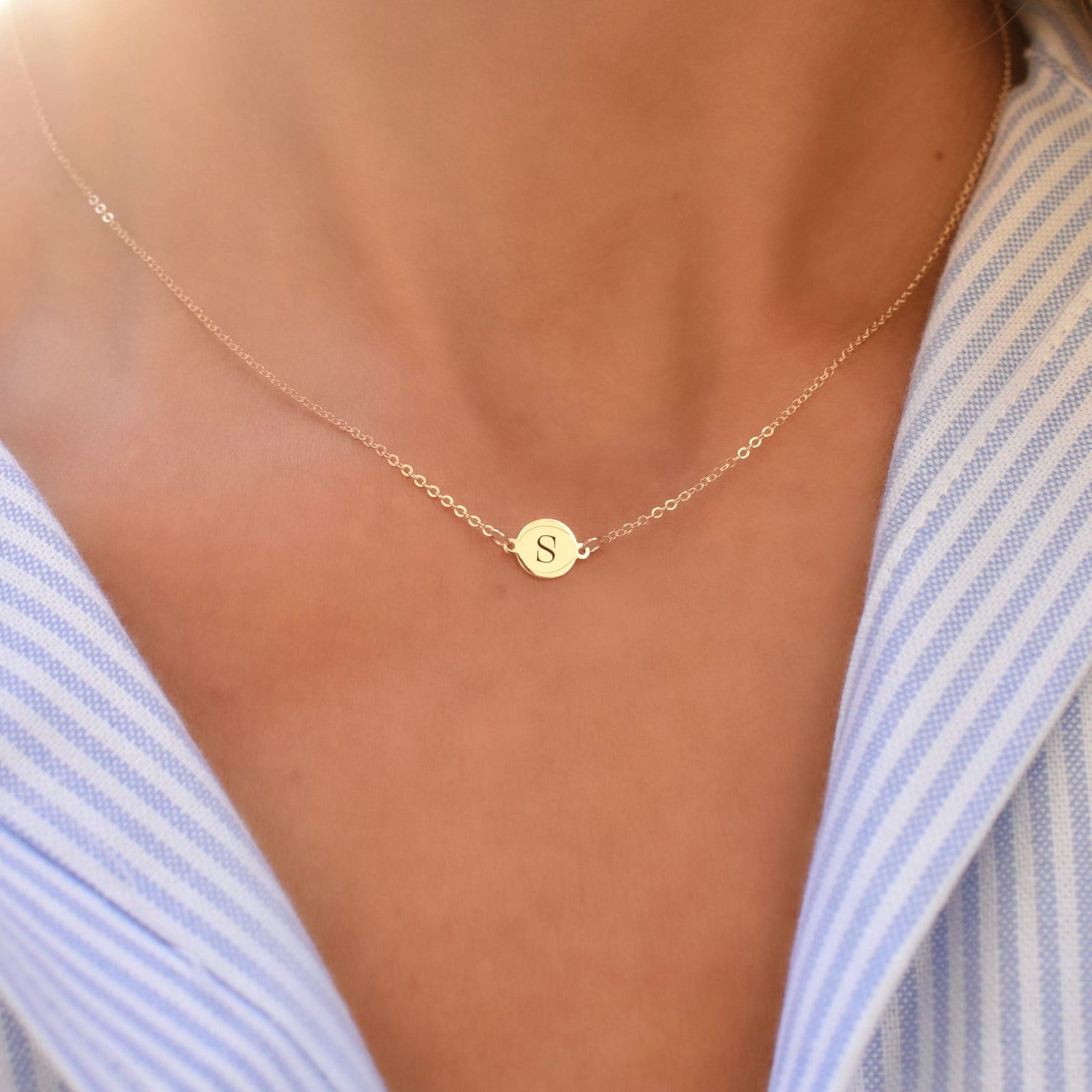 Woman wearing a 14k yellow gold cable chain necklace featuring one 1/4” flat disc engraved with the letter S