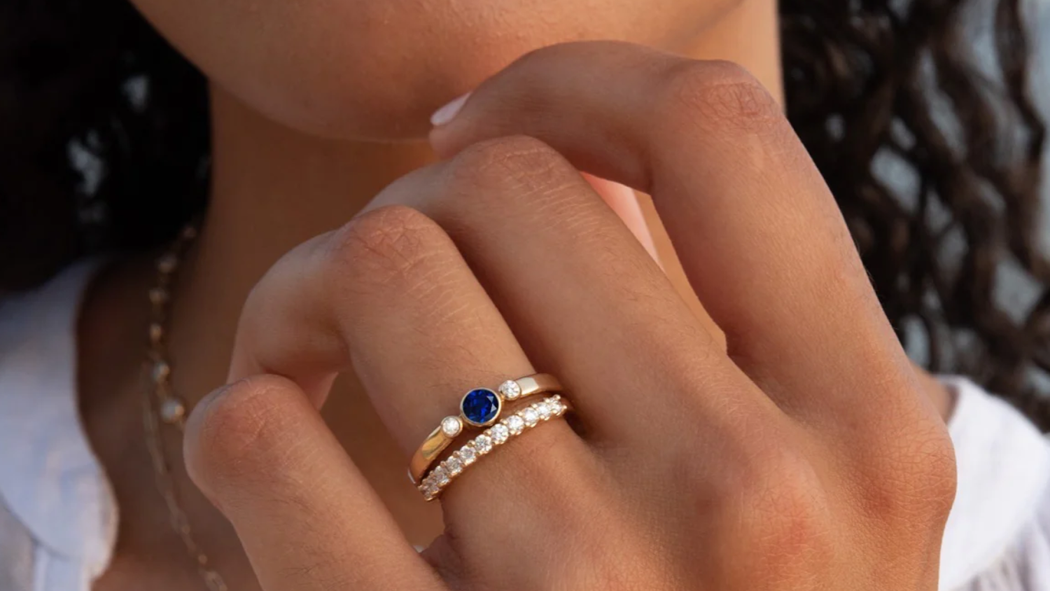 A Model Wearing A Ring With Sapphires And Diamonds