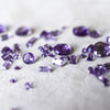 Amethyst gemstones of various cuts scattered on a white background