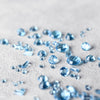 Nantucket Blue Topaz stones of various cuts scattered on a white background