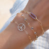 An Adelaide 1 Pavé Amethyst Link bracelet, a personalized Newport bracelet, and a Peace Sign Adelaide Mini bracelet.