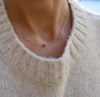 Woman wearing a personalized Classic 3 Birthstone necklace featuring 4mm moonstone, sapphire, and Nantucket blue topaz.
